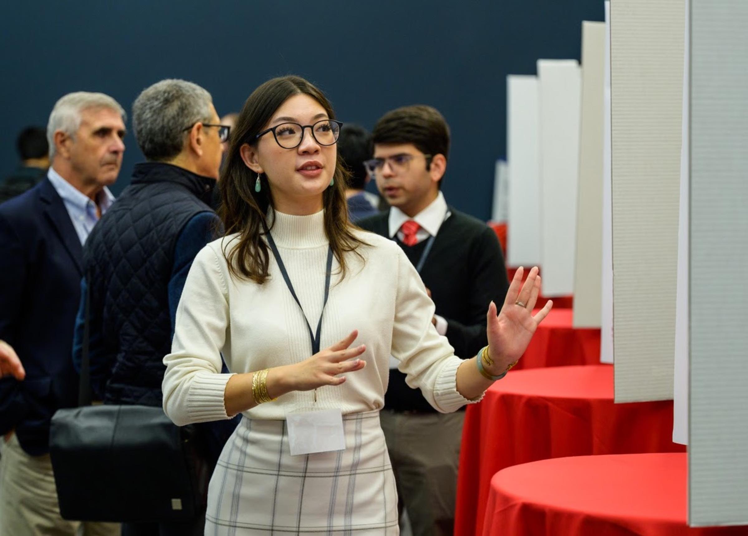 Student describing research to a crowd of onlookers at Stevens event