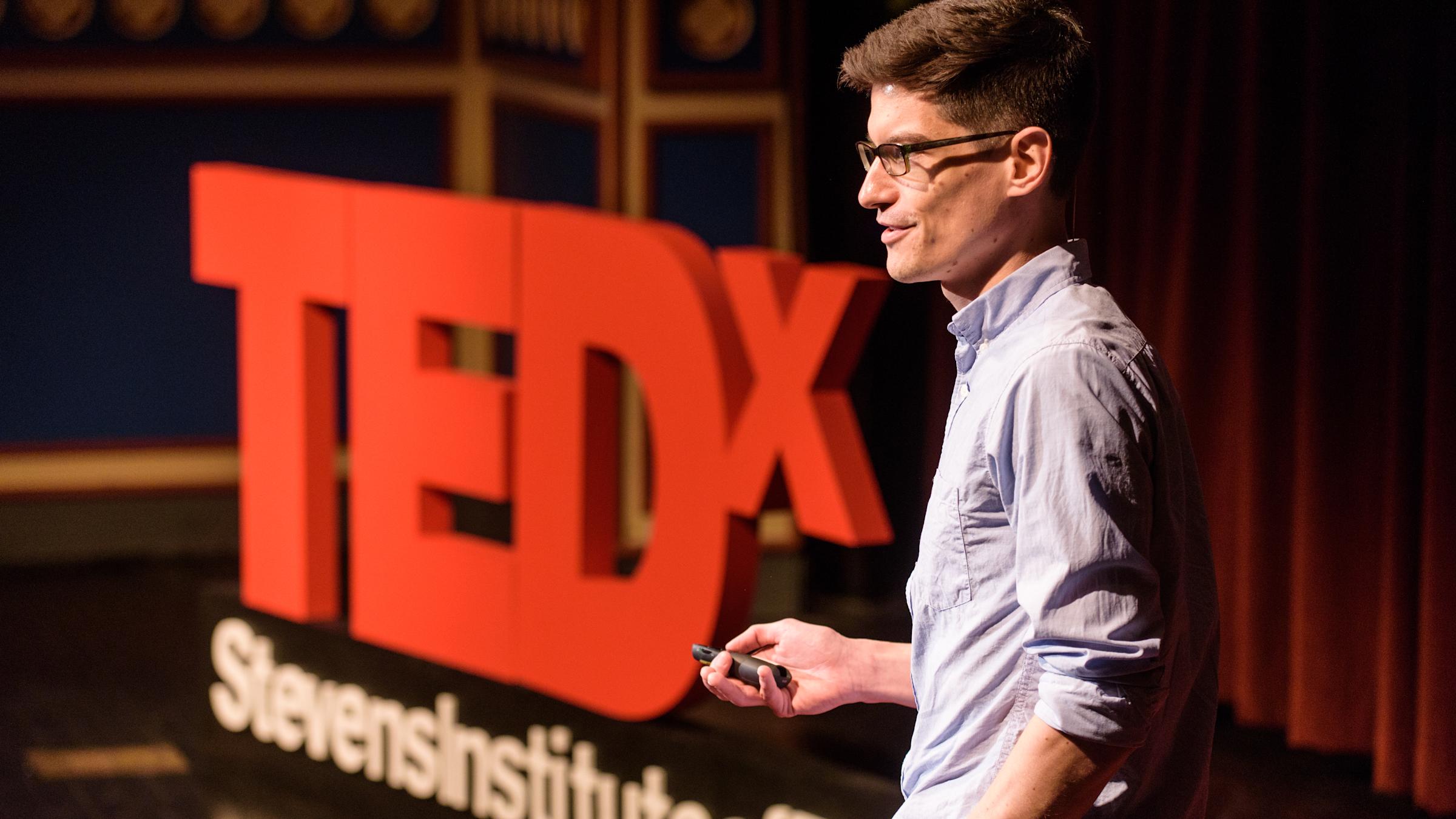 Jan Cannizzo on stage with a TEDx Talk display.