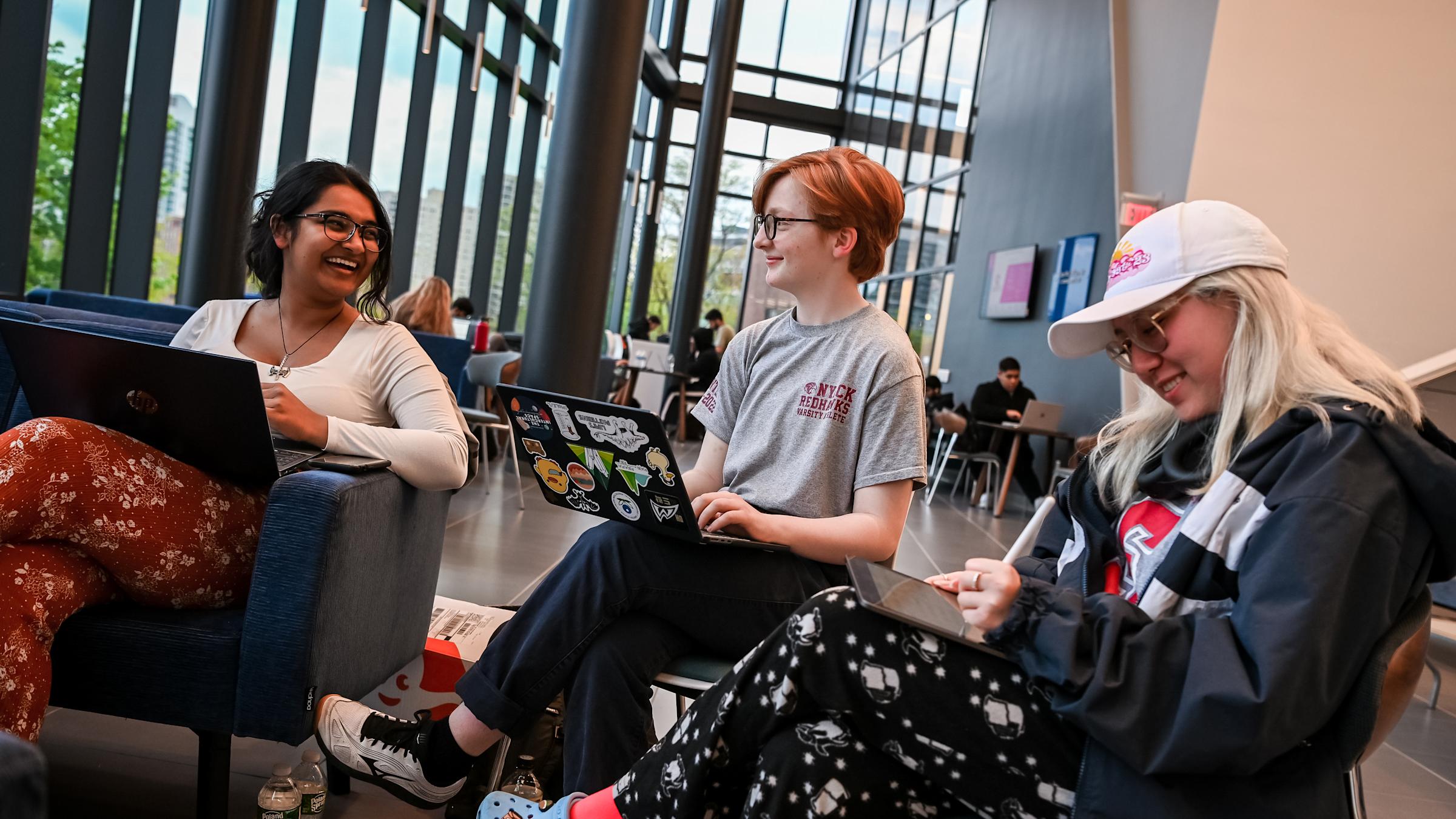 Image of students talking while having their laptops on their laps.