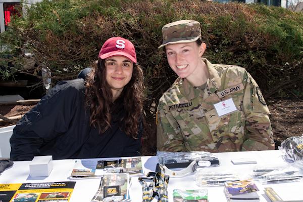 Students at table, one in uniform, share information about military programs at Stevens