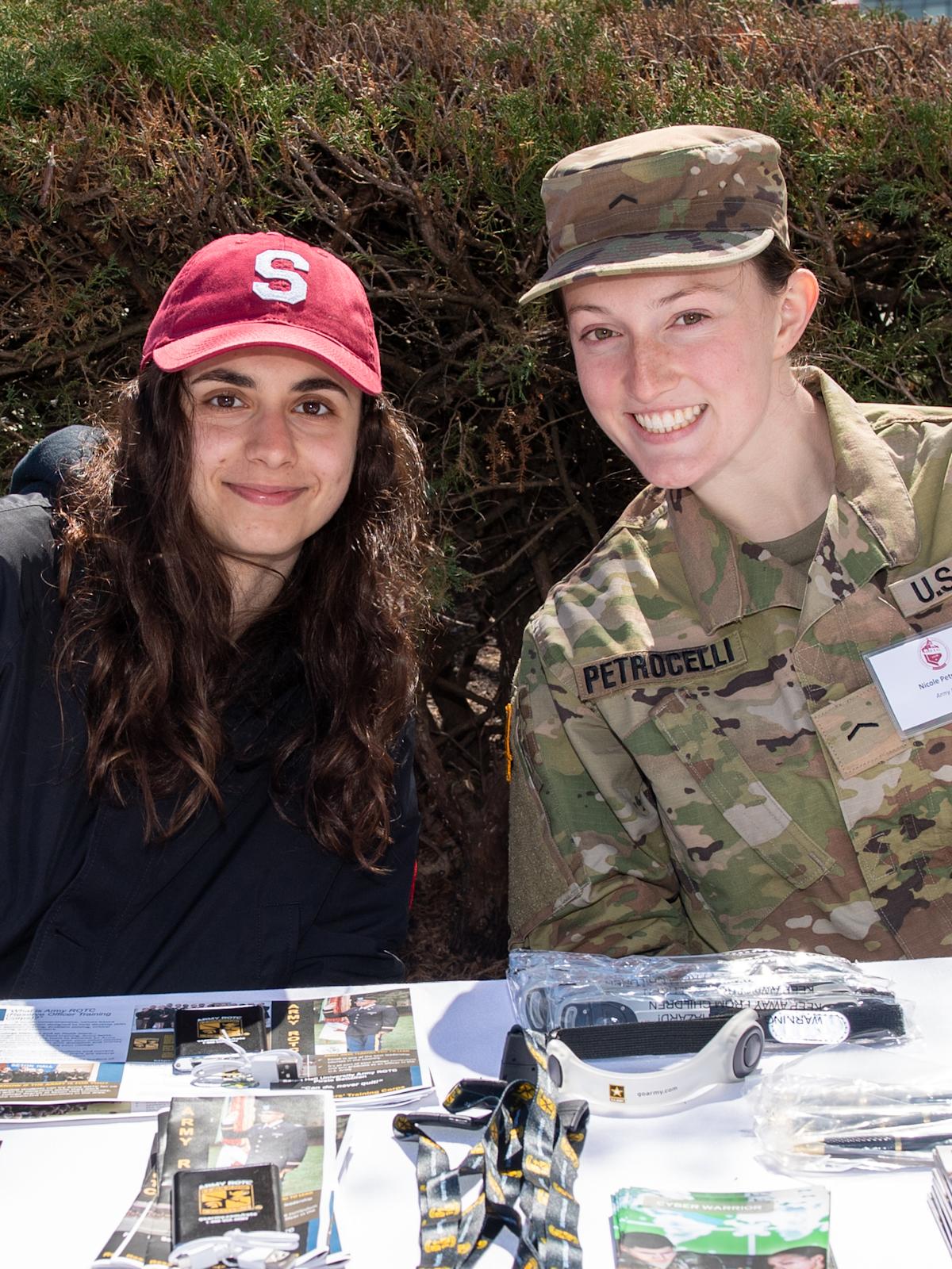 Students at table, one in uniform, share information about military programs at Stevens