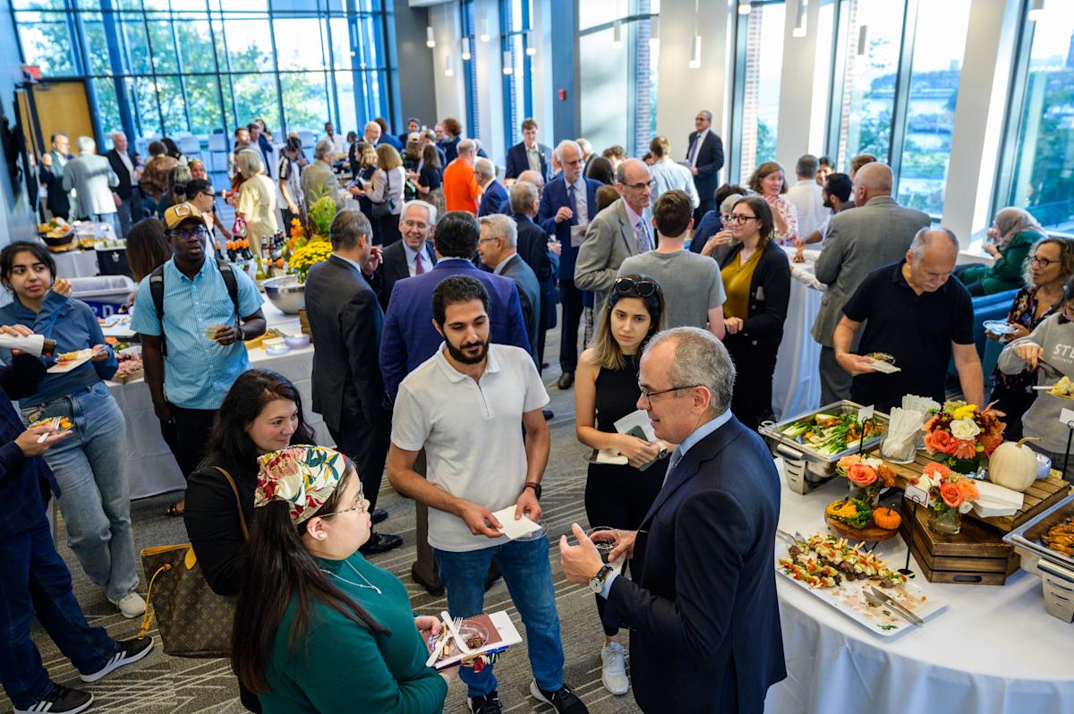 Attendees gather and mingle in the University Center Complex Gallery room for a reception and networking