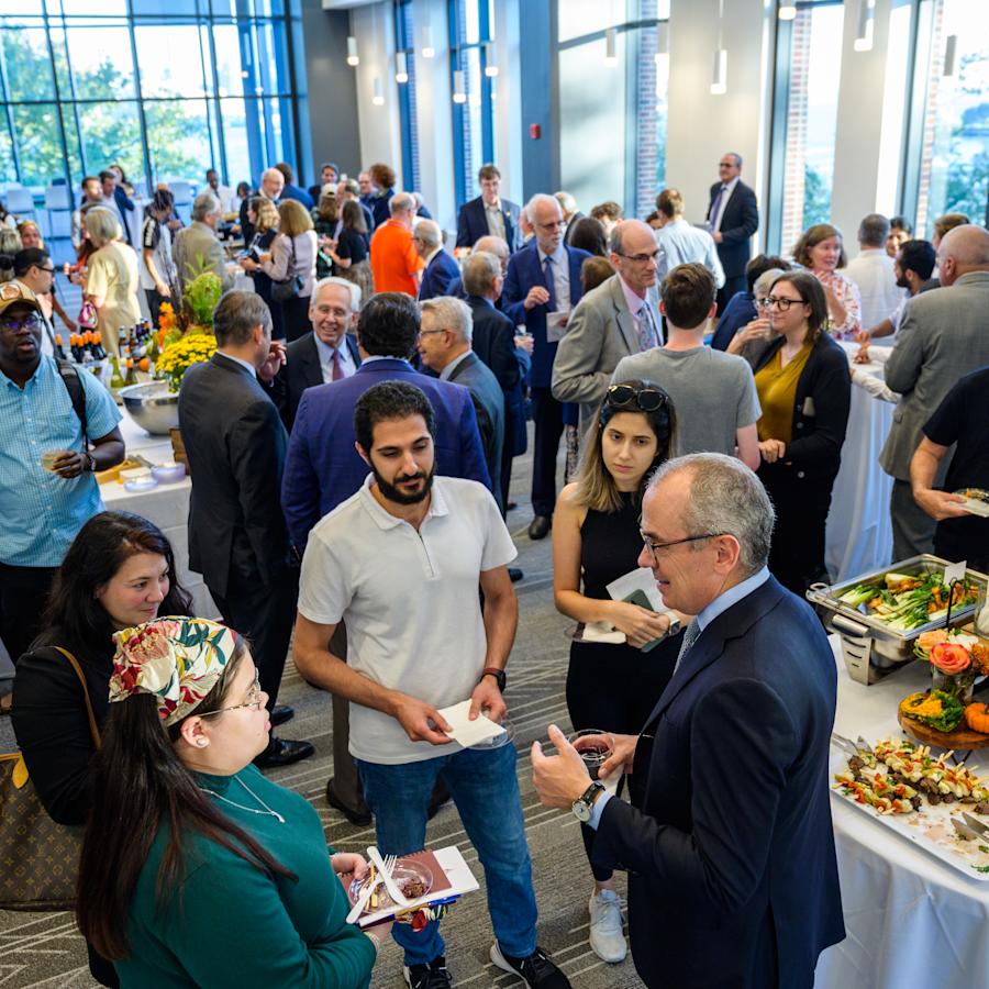 Attendees gather and mingle in the University Center Complex Gallery room for a reception and networking