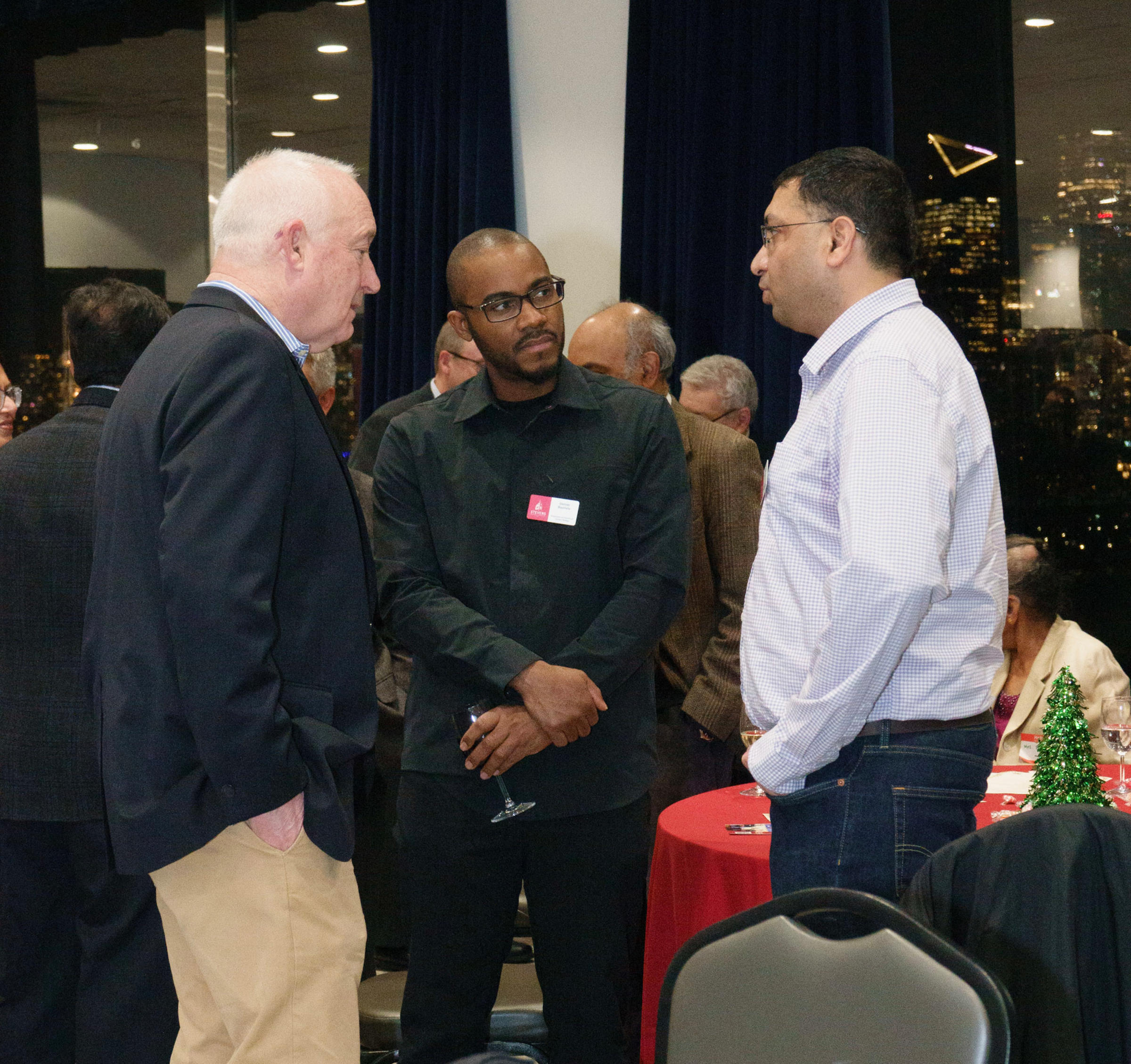 Photo of three men standing and talking, with Denver Baptiste in the middle