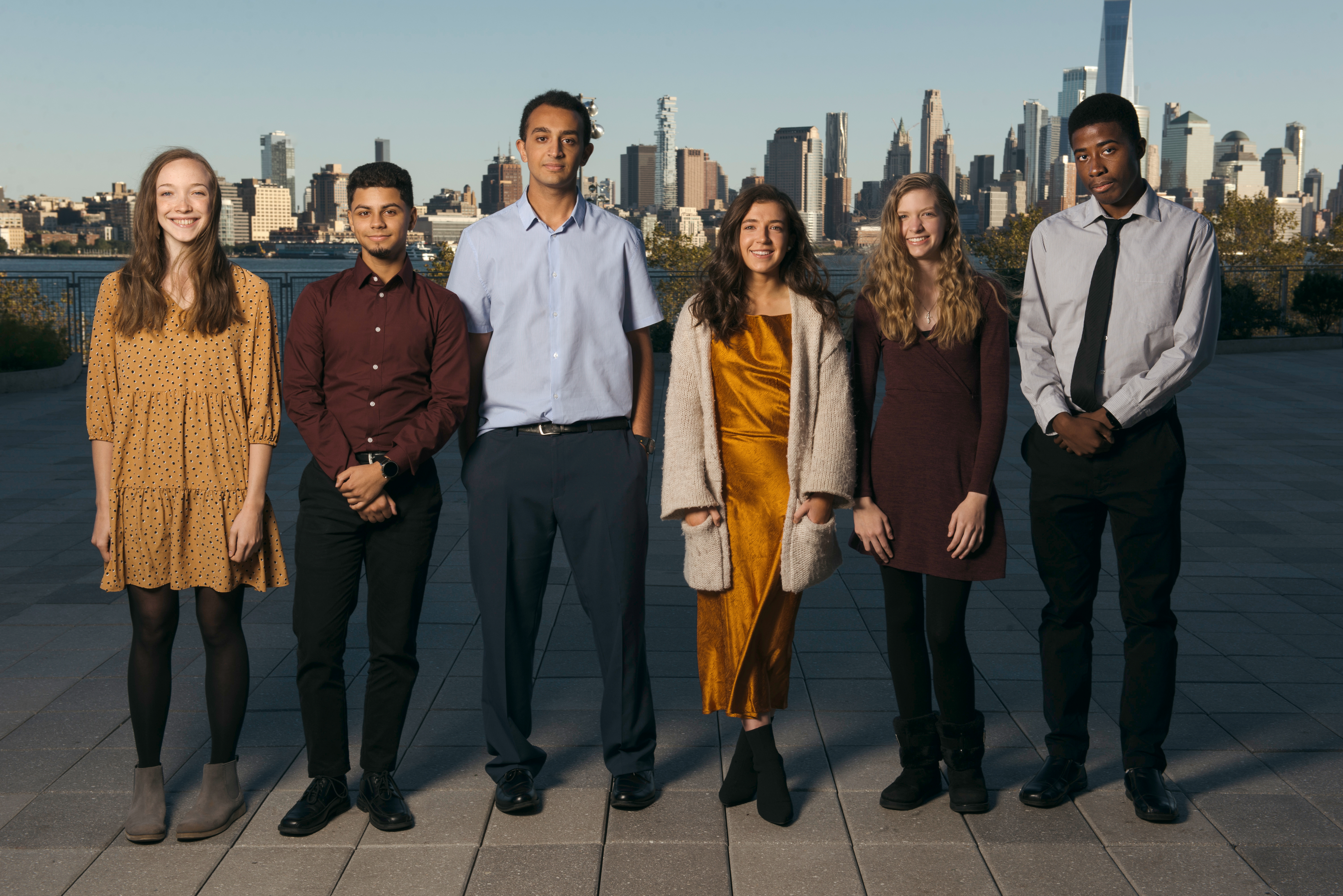 Group of six students pose in front of New York skyline.