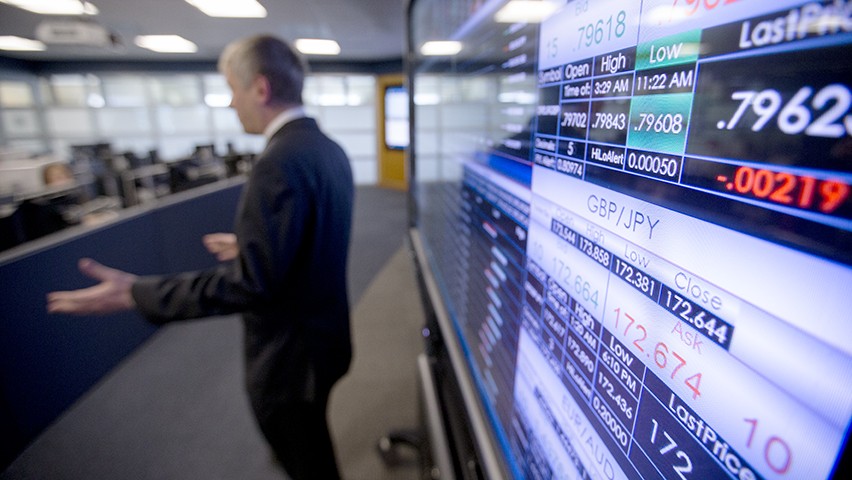 A professor speaking to a class in the high-tech Hanlon Financial Systems Center. A real-time stock ticker is shown in the foreground.