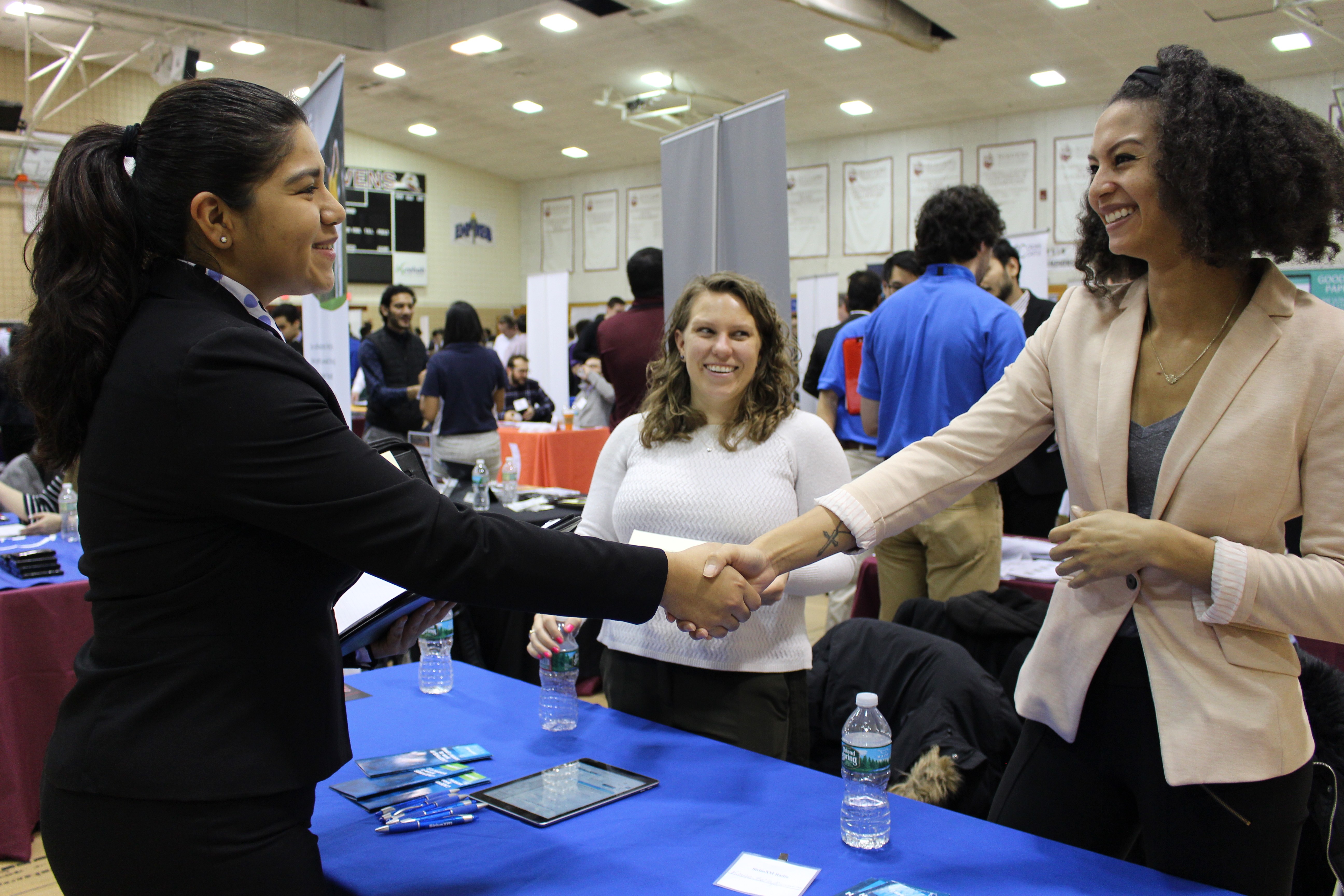 Female student on the left shakes hands with a female recruiter on the right