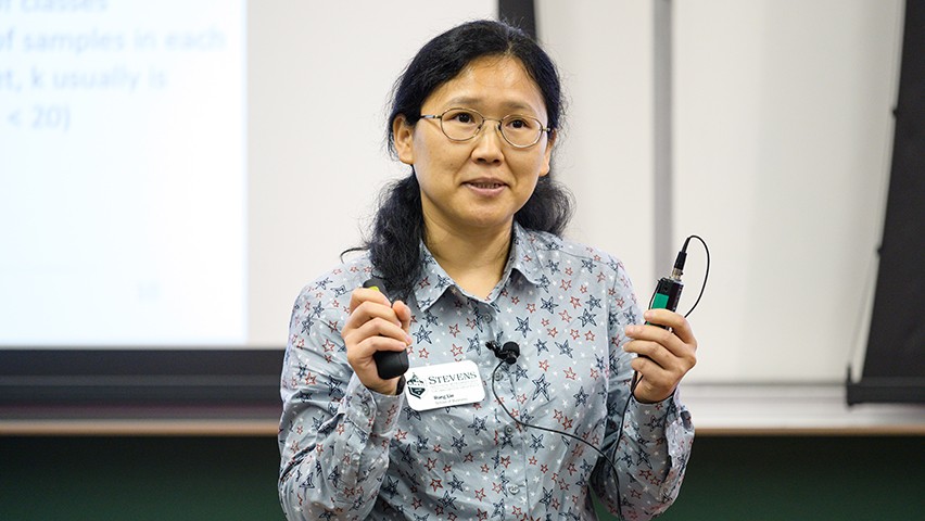 Dr. Emily Liu stands before a screen showcasing the model she built to solve a reviewing issue for a life sciences company.