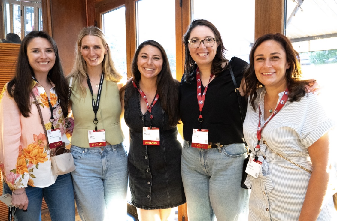 A group of five young alumni smile at a Graduates of the Last Decade event