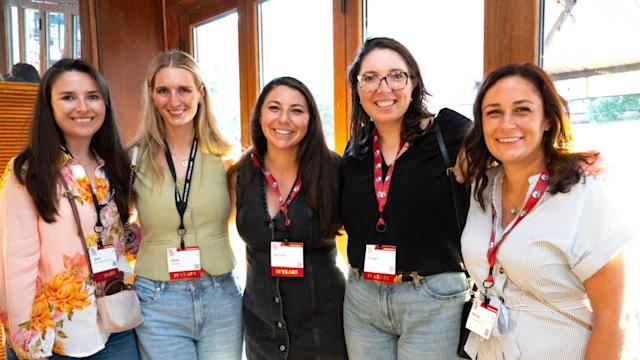 A group of five young alumni smile at a Graduates of the Last Decade event