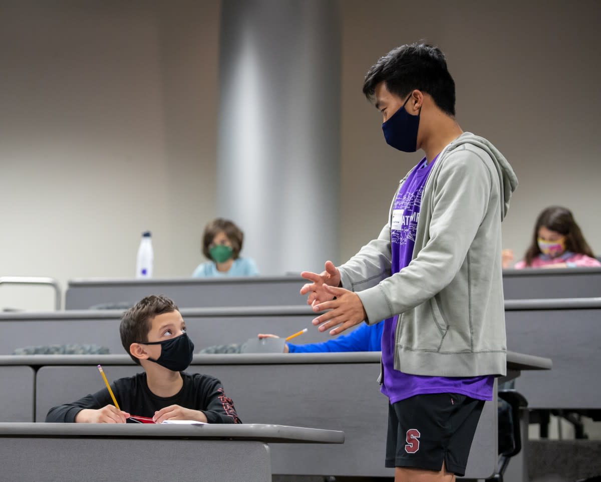 Math Olympiad volunteer assisting participant during testing