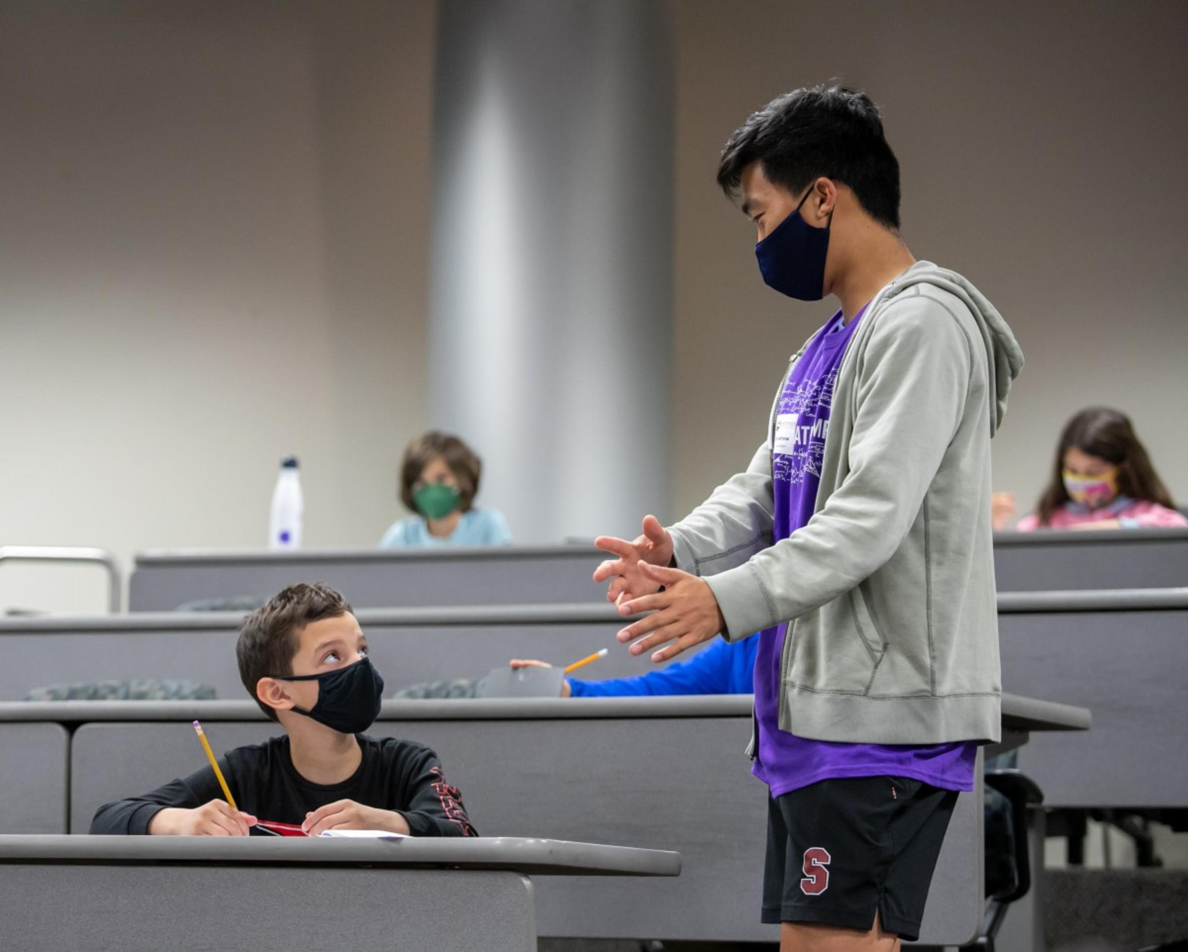 Math Olympiad volunteer assisting participant during testing