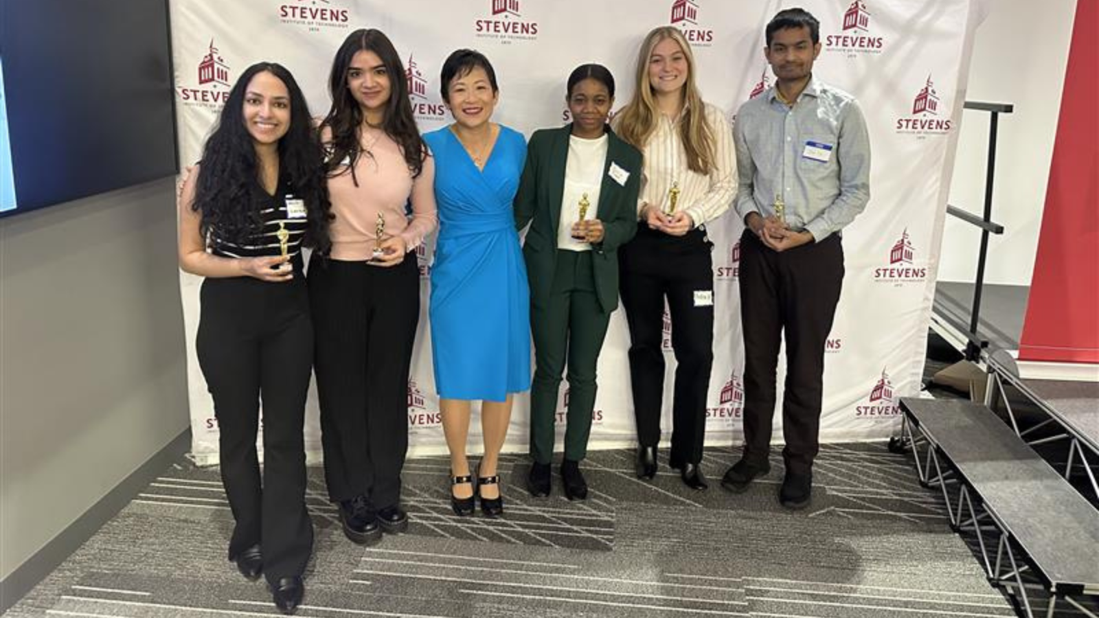 Students in the Department of Biomedical Engineering pose in front of a Stevens Institute of Technology backdrop with Jennifer Kang-Mieler, who is the department chair of the Department of Biomedical Engineering.