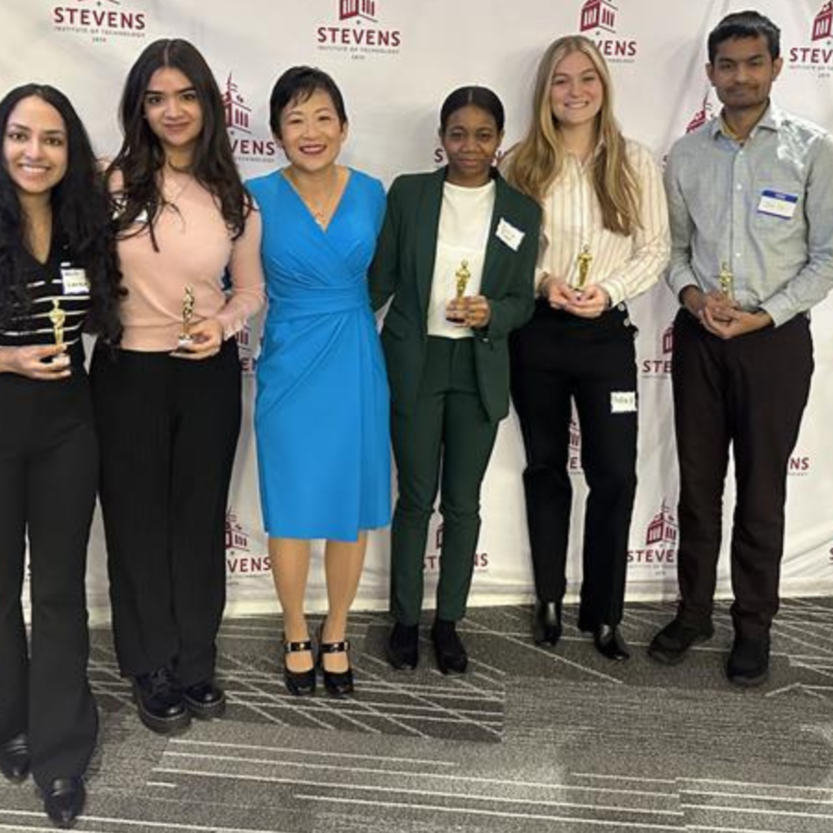 Students in the Department of Biomedical Engineering pose in front of a Stevens Institute of Technology backdrop with Jennifer Kang-Mieler, who is the department chair of the Department of Biomedical Engineering.
