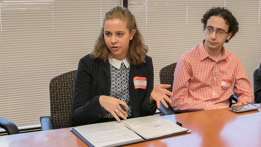 Joyce Pegler, in a dark jacket, seated next to a male student at a conference table.
