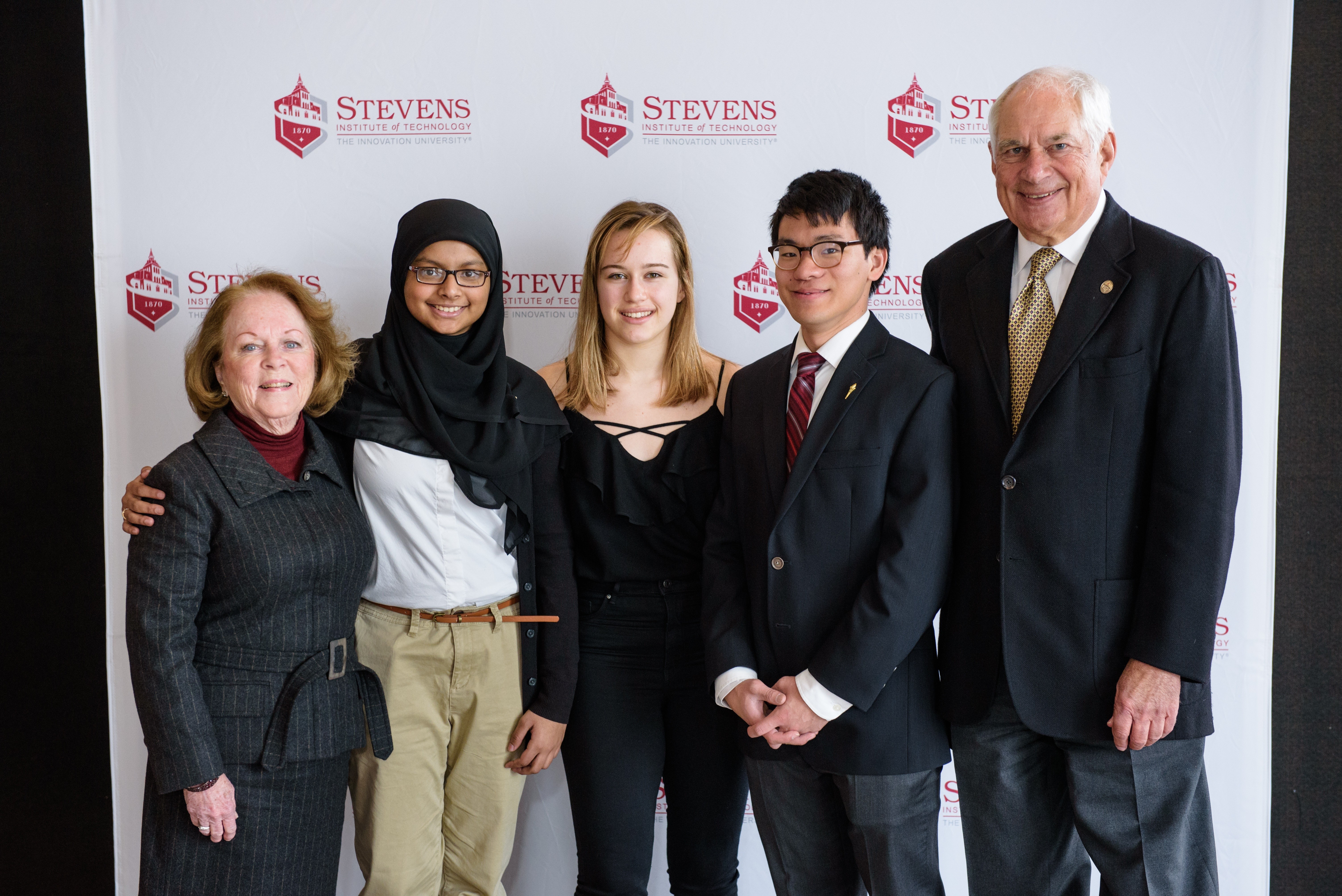 Students and alumni pose in a group of five 