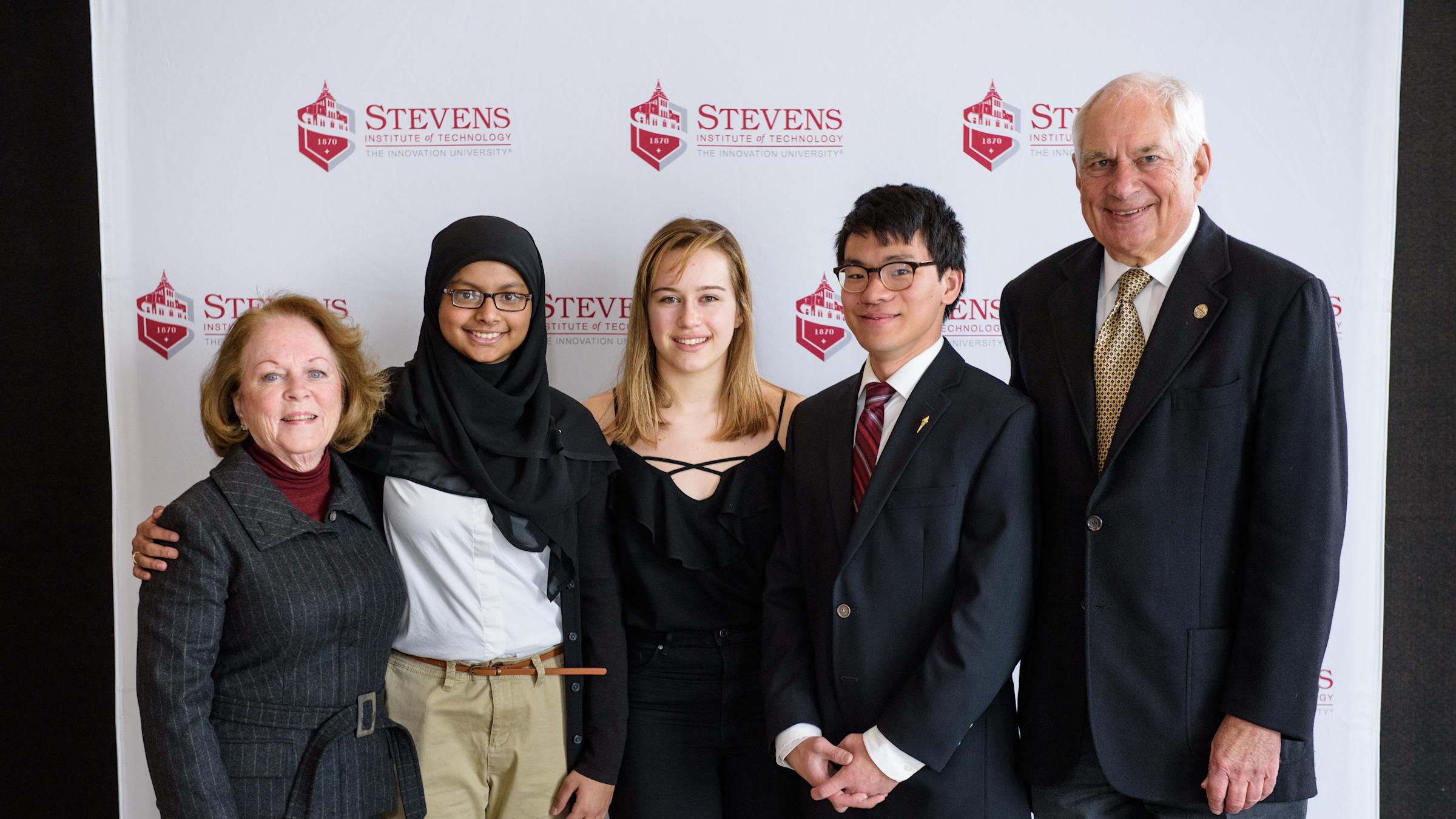 Students and alumni pose in a group of five