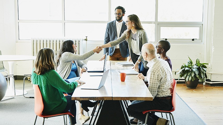 A group of young professionals meeting in a modern, open-space office at a tech startup.