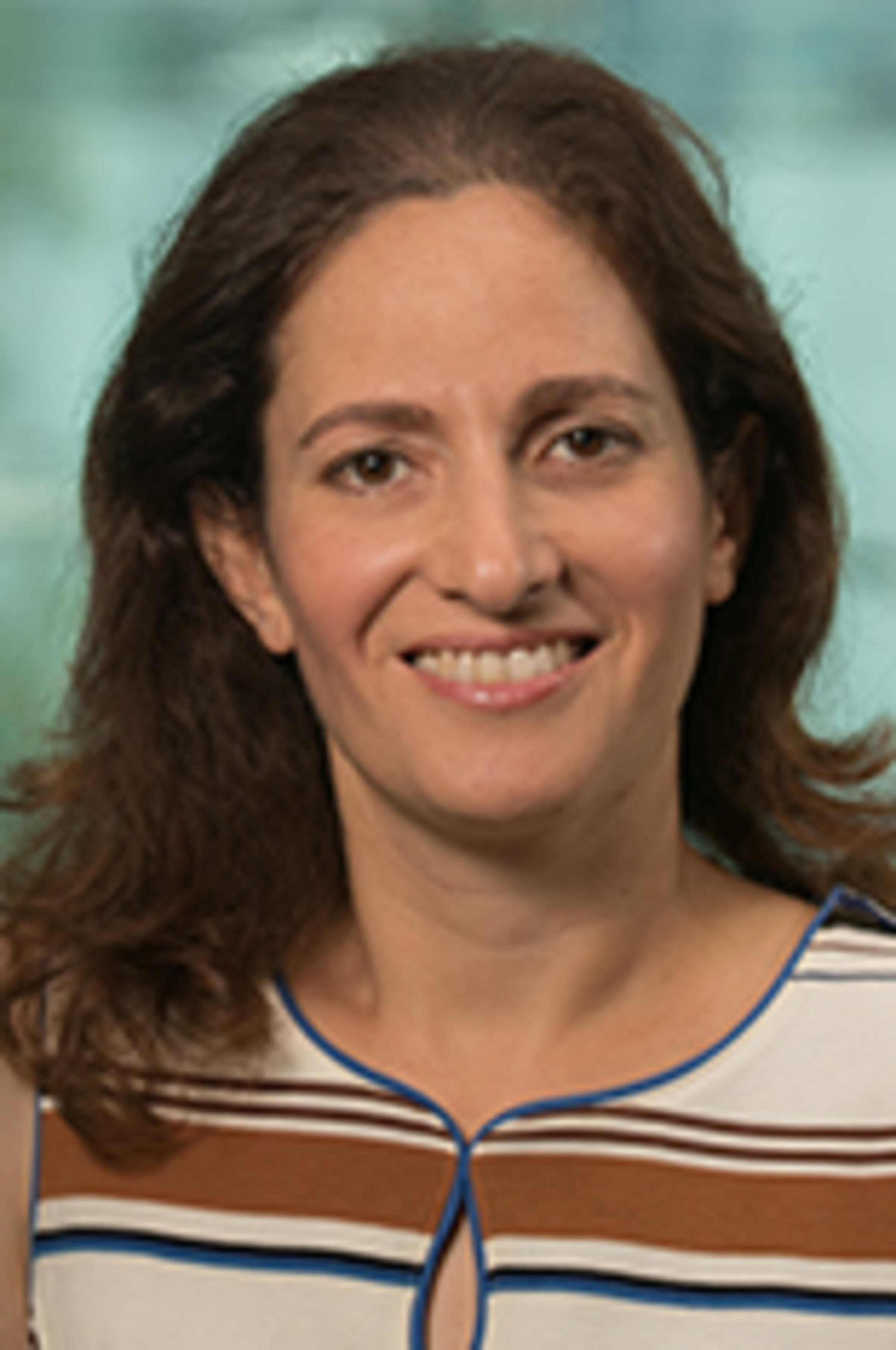 Headshot of Dr. Joelle Saad-Lessler in a striped dress with the Manhattan skyline in the background.