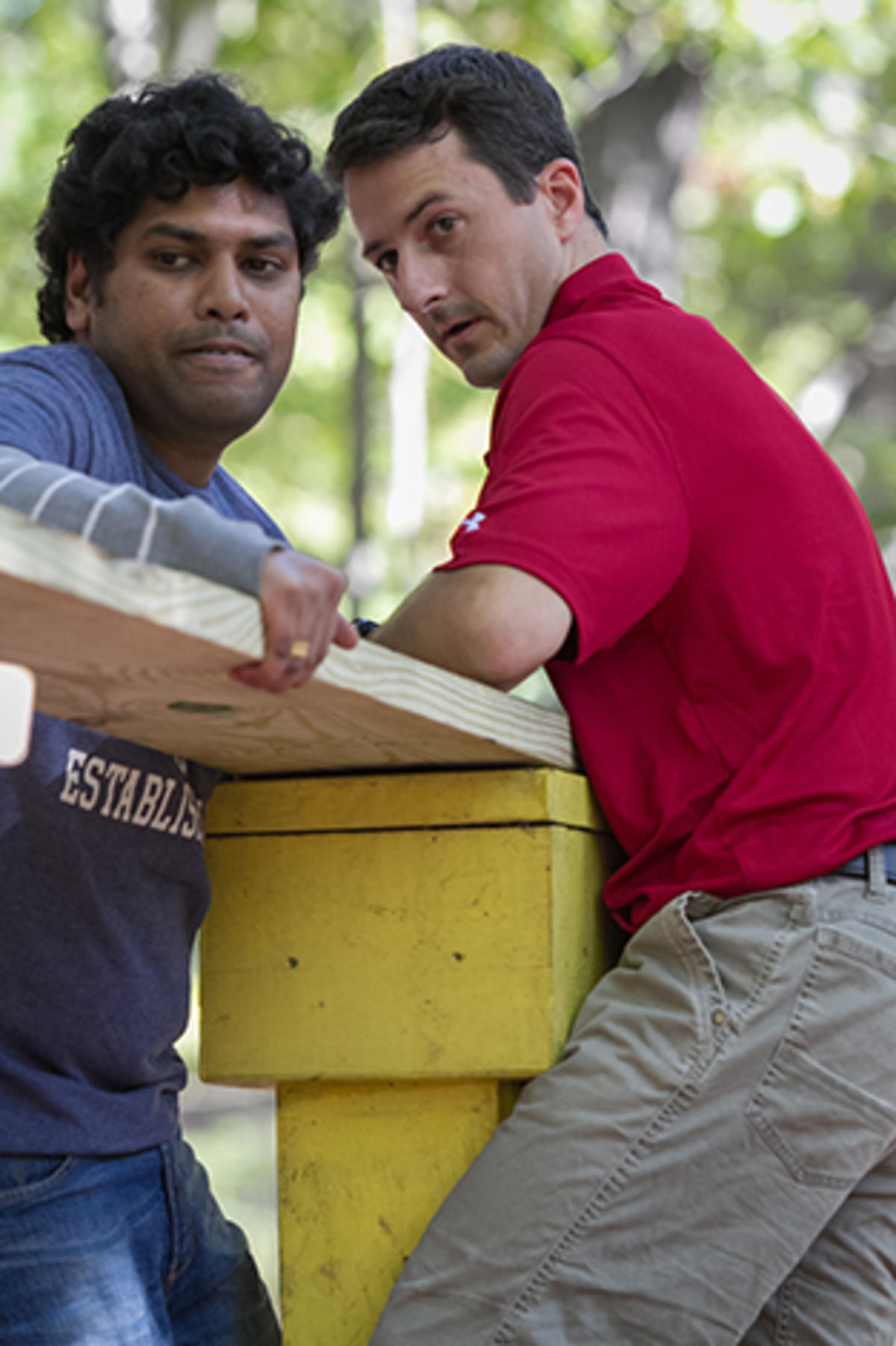Two students support a plank for their classmates.