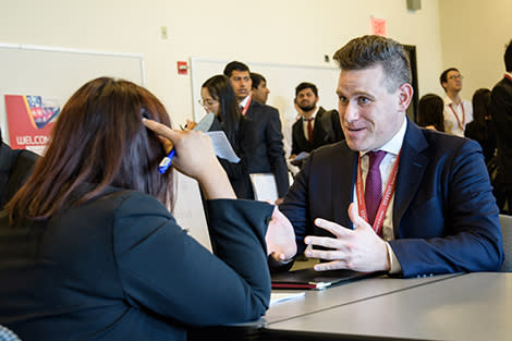 A male student gestures to a female recruiter on the Stevens campus.