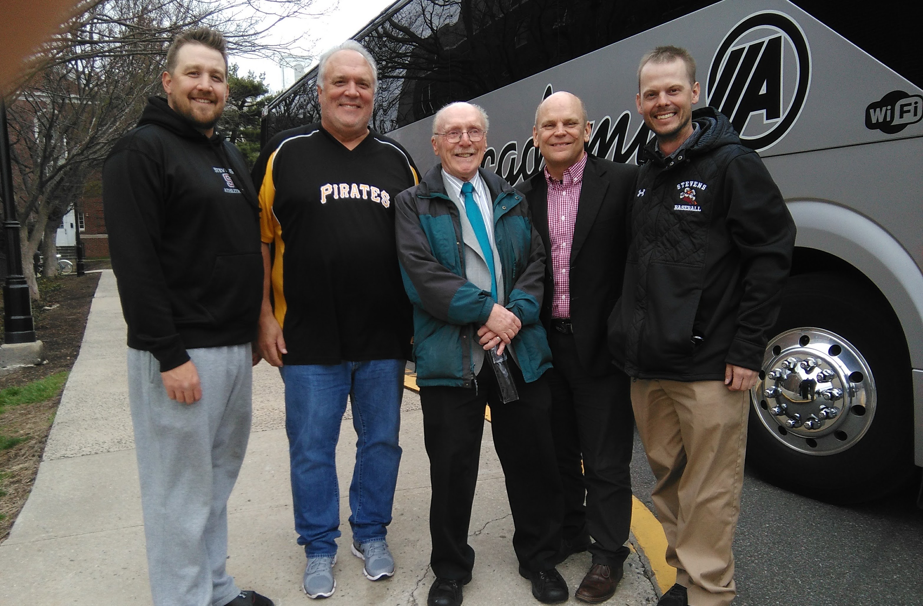 Five white men stand outside a bus