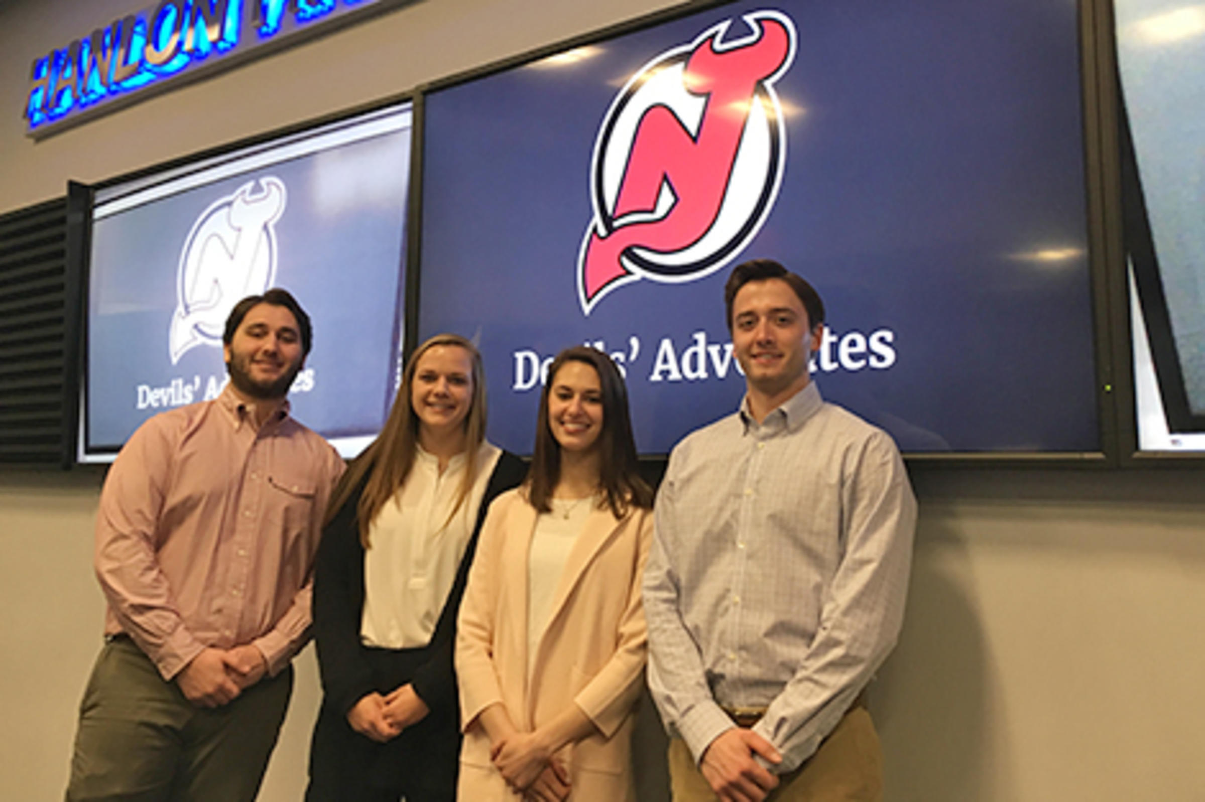 Four students in the Hanlon Lab with a slide presentation displayed onscreen.