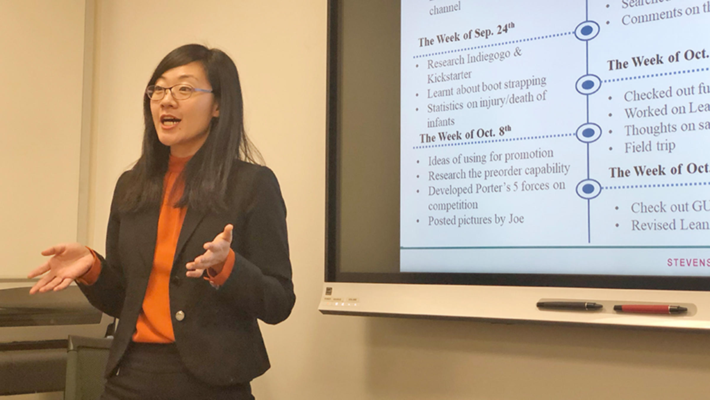 An MBA student leads a presentation on the Stroller Controller in a conference room.