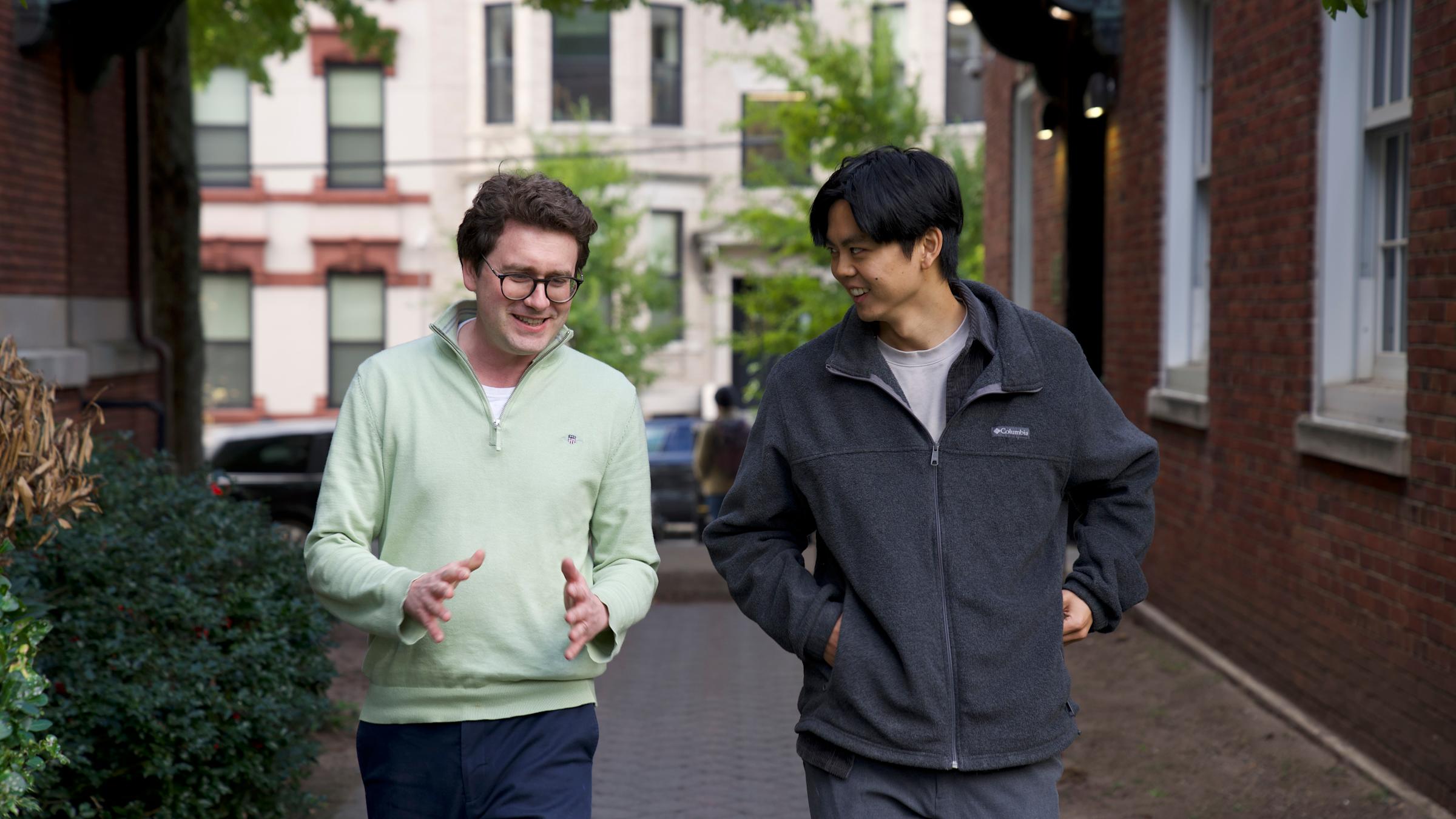 Two males - Professor Igor and student walking on campus having a conversation
