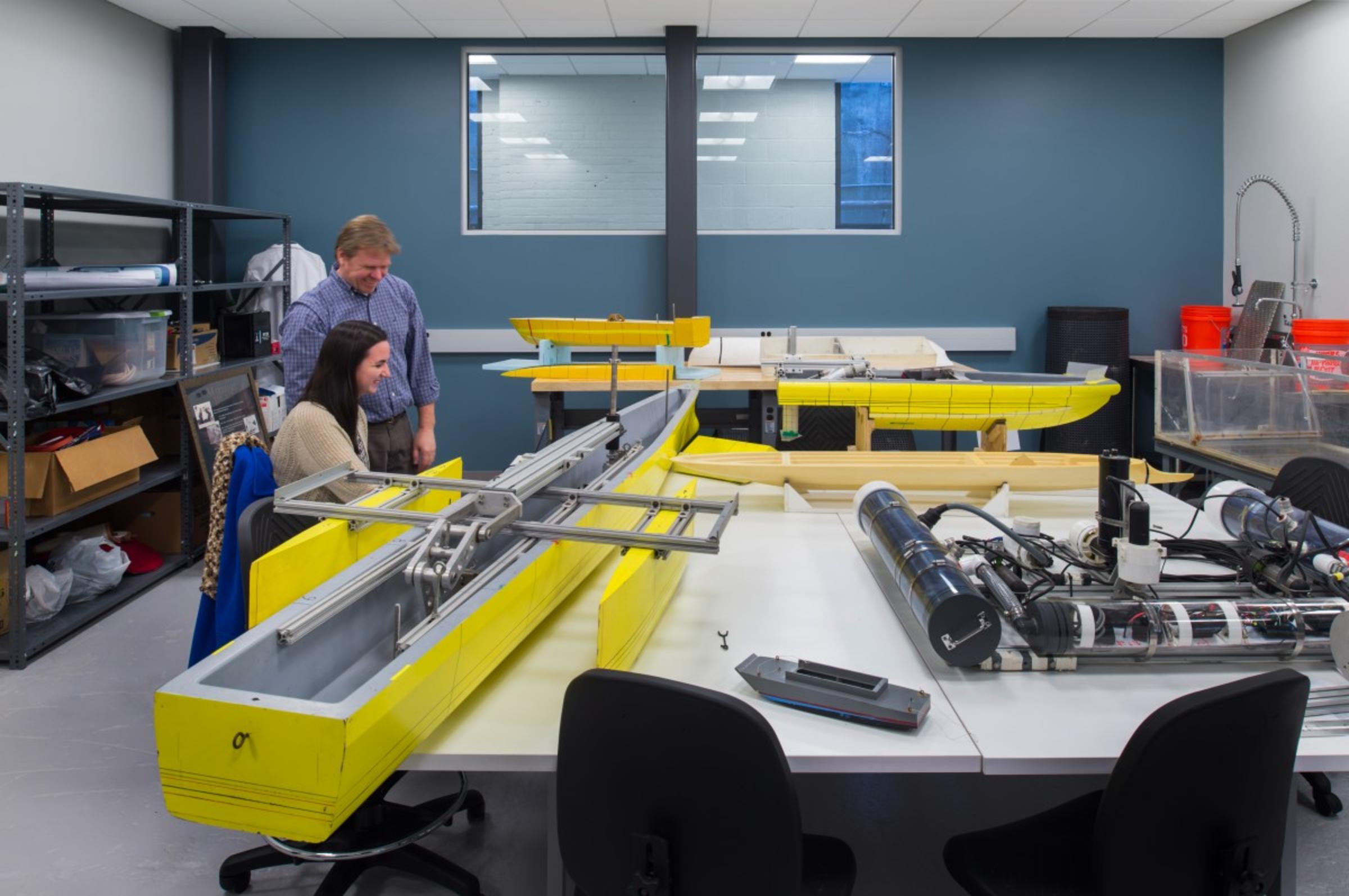 Professor Michael DeLorme works with a student to build a boat in the ABS lab