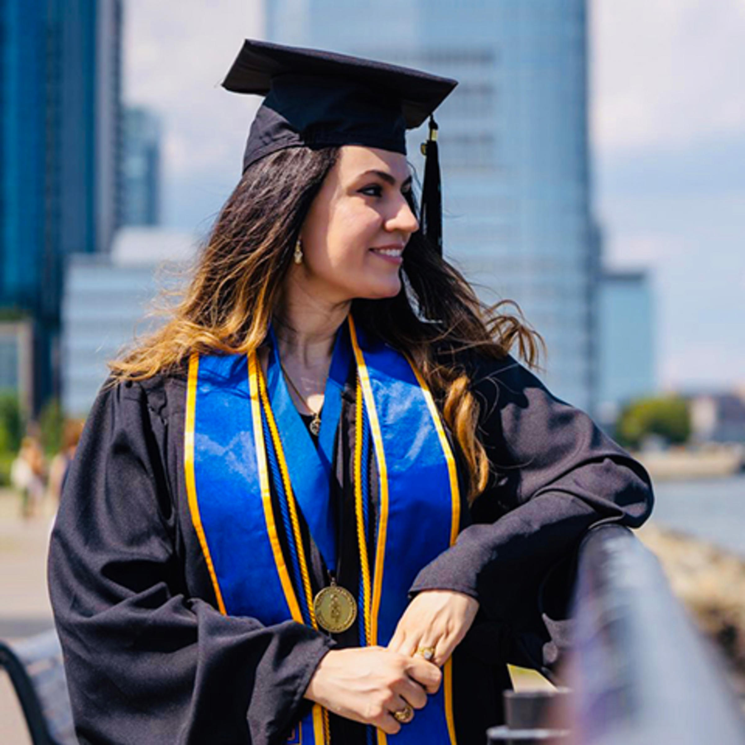 Fatine Zaaj, in cap and gown, on the Hudson River in Jersey City.