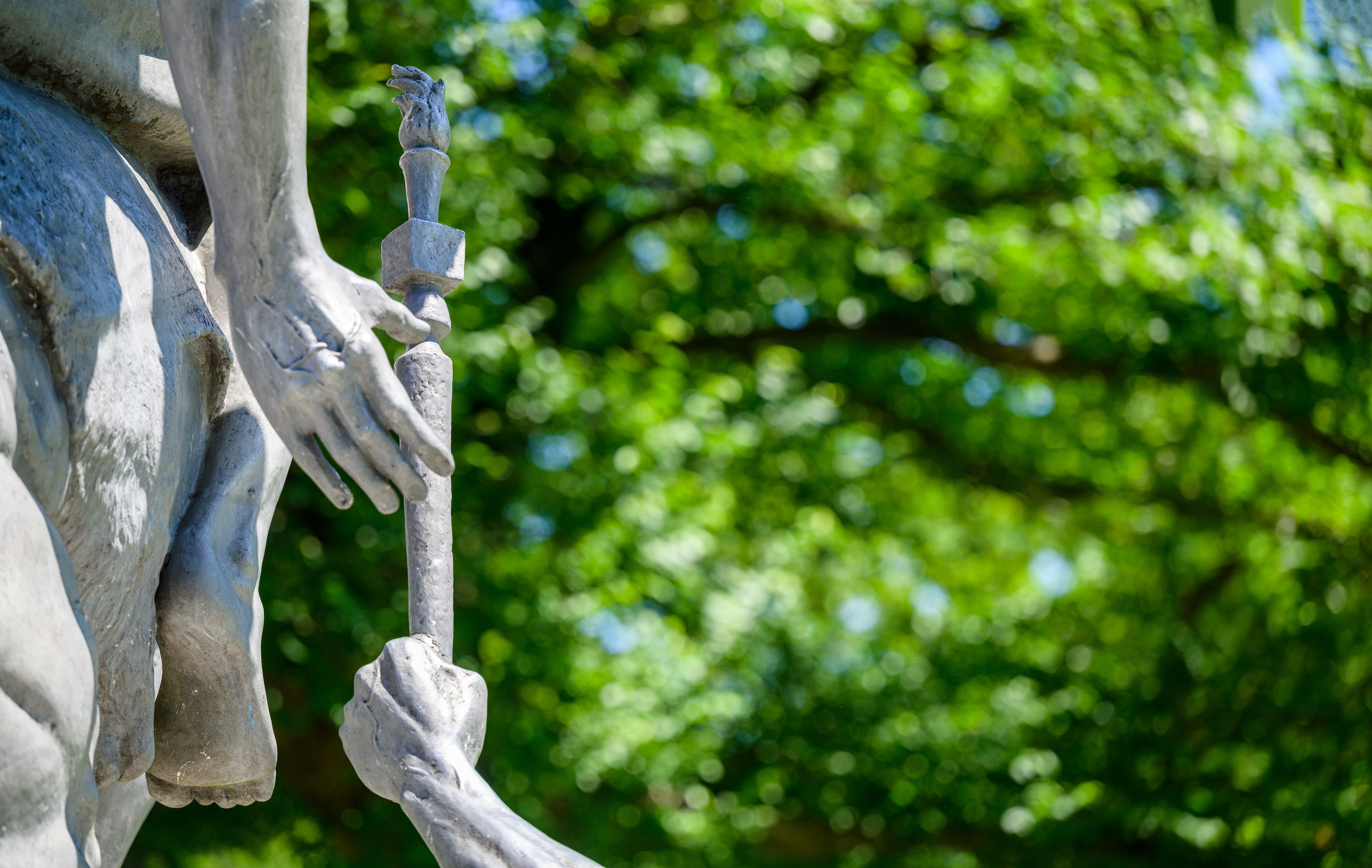 Zoomed in photo of The Torch Bearers Sculpture - a cast aluminum sculpture depicting a man on the ground passing a torch to a man on a horse