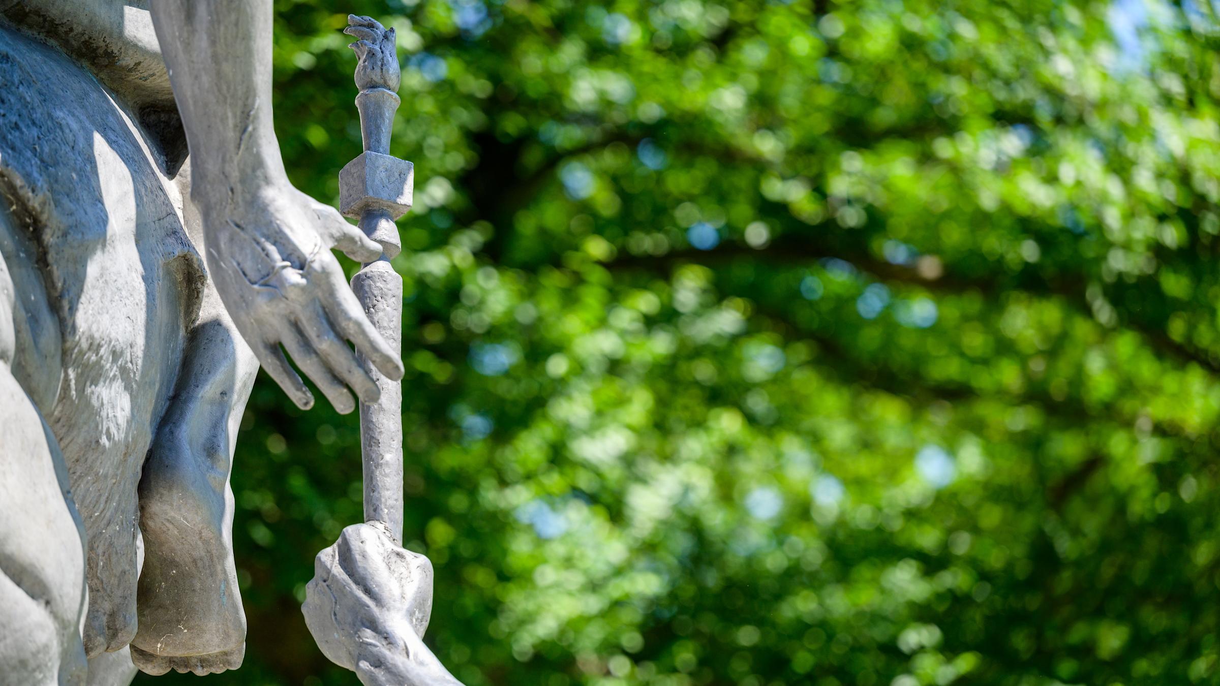 Zoomed in photo of The Torch Bearers Sculpture - a cast aluminum sculpture depicting a man on the ground passing a torch to a man on a horse