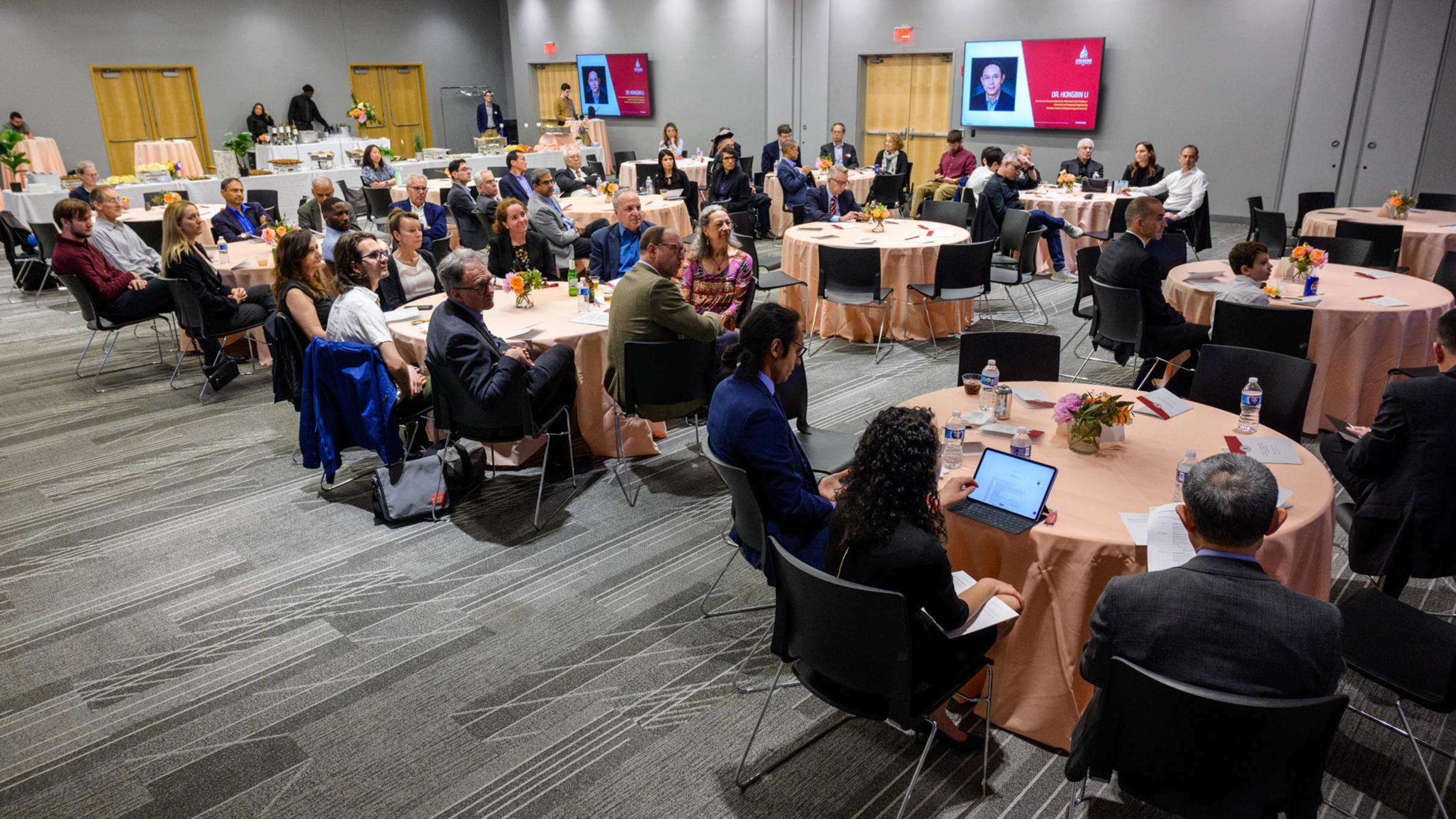 A wide shot of the room with people looking at the stage.