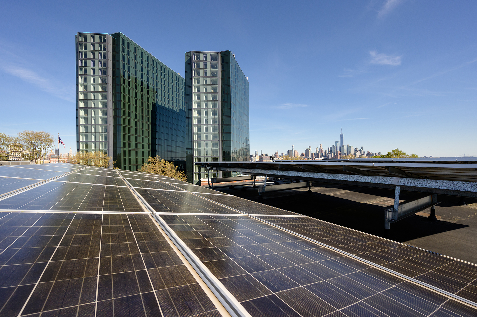An array of solar panels on the roof of a building with the UCC office and residence halls in the distance behind.