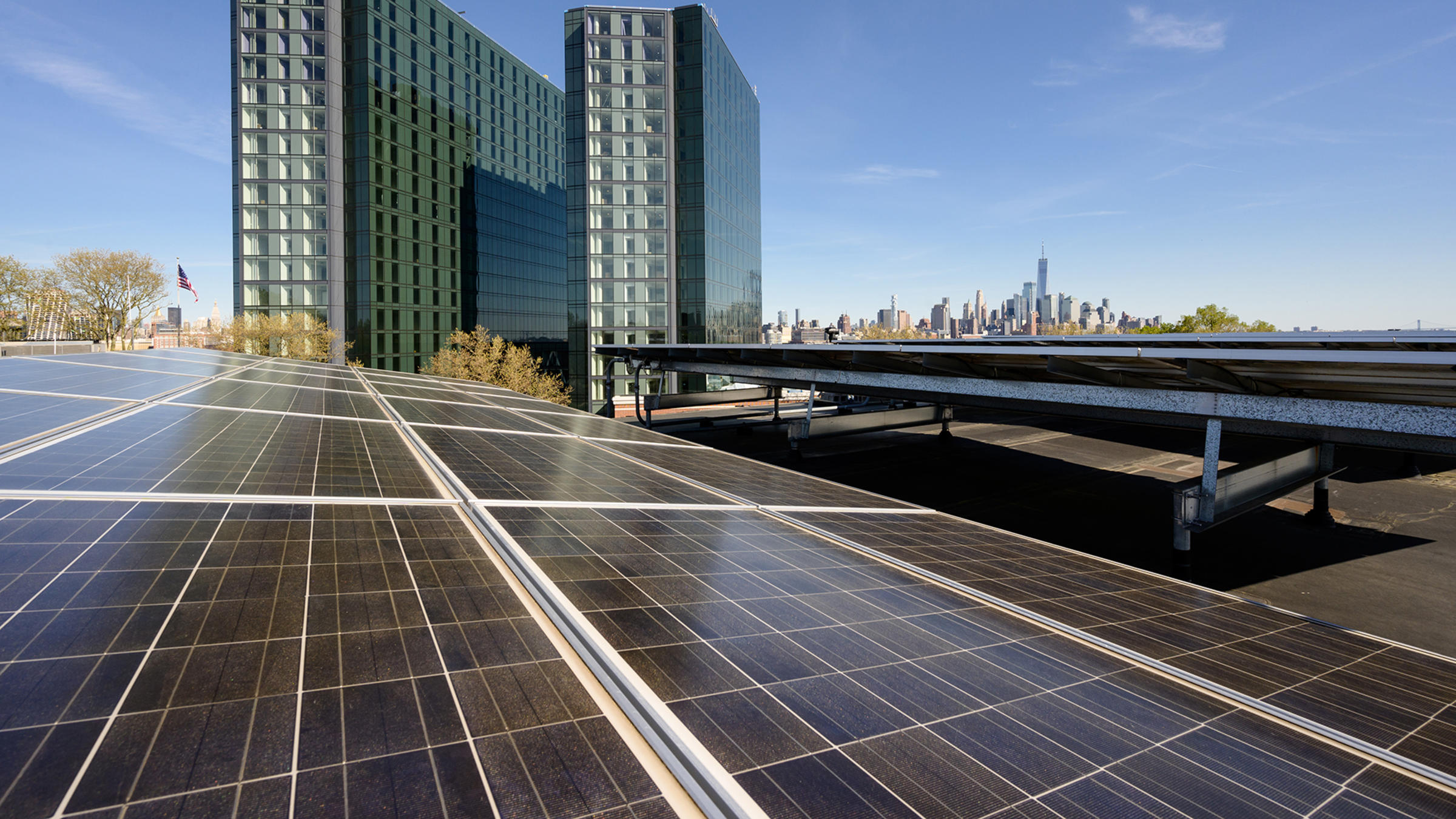 An array of solar panels on the roof of a building with the UCC office and residence halls in the distance behind.