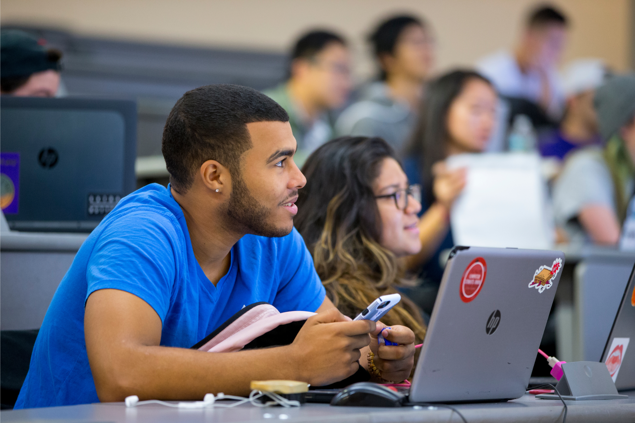 Two students of color looking at laptop computers from desks in a classroom