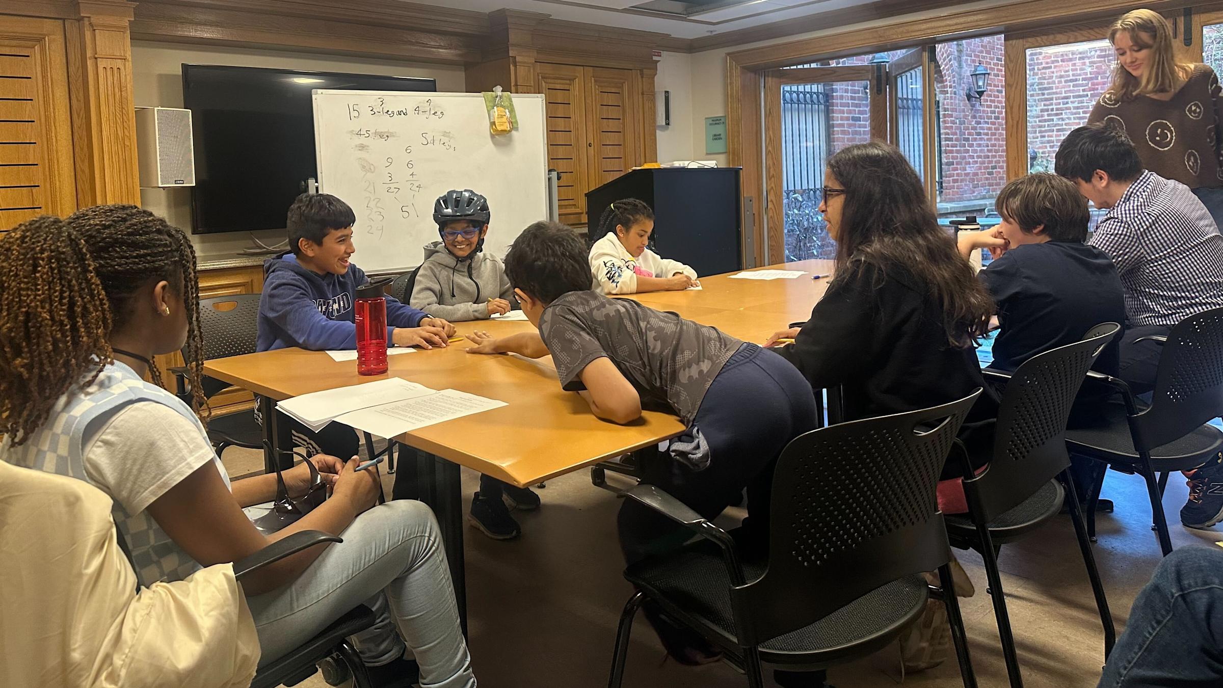 children seated around a table, smiling and laughing while interacting with one another