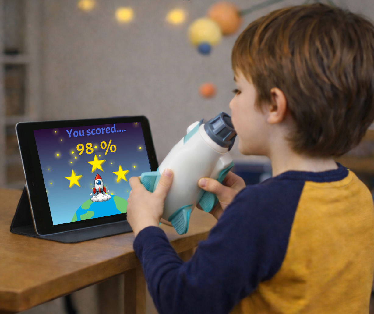 A child using a prototype of RocketLungs while watching an accompanying monitor for the device.
