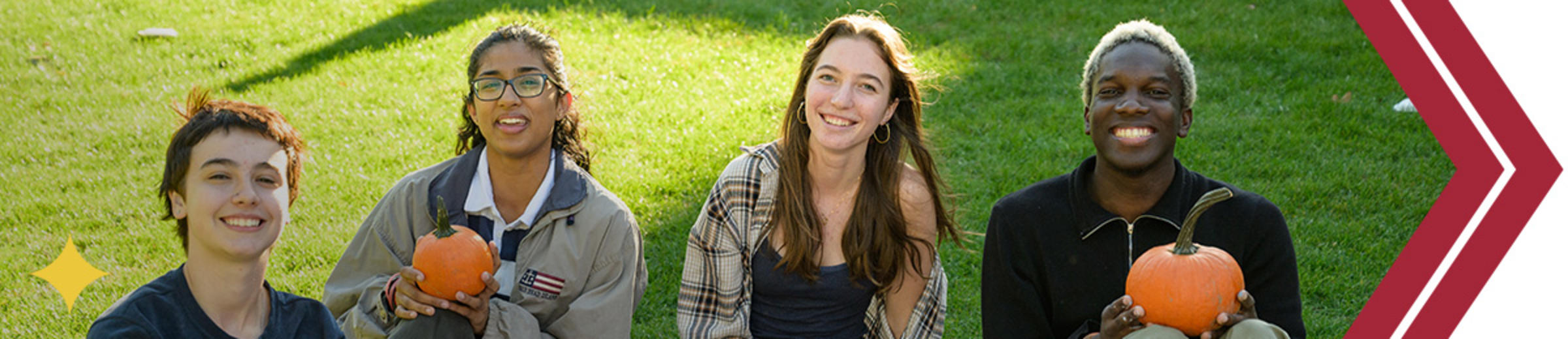 Group of four students smile holding pumpkins
