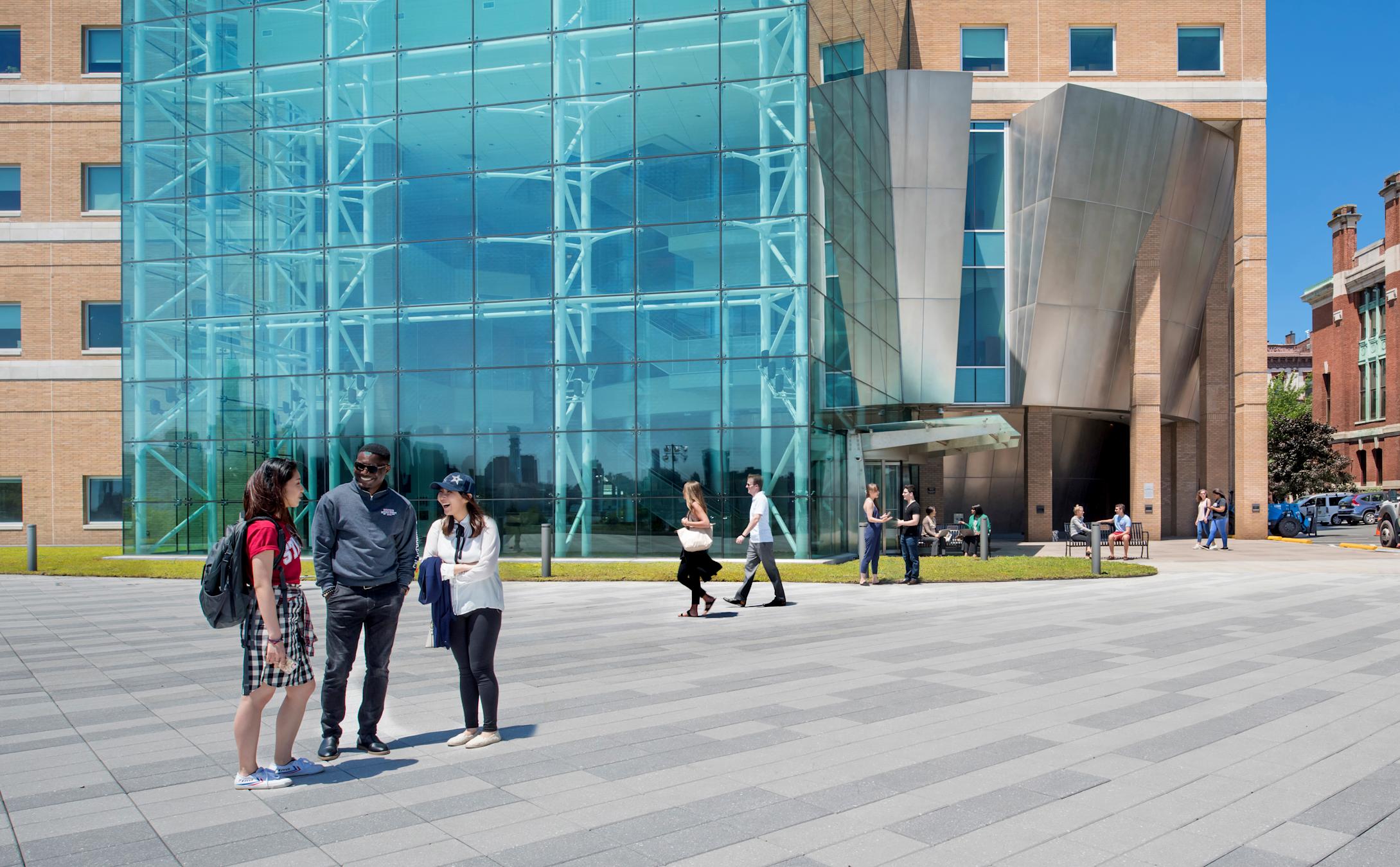 Three students smiling and laughing on plaza outside Babbio Center.