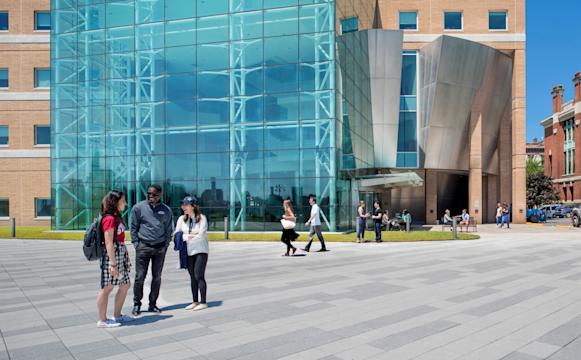 Three students smiling and laughing on plaza outside Babbio Center.