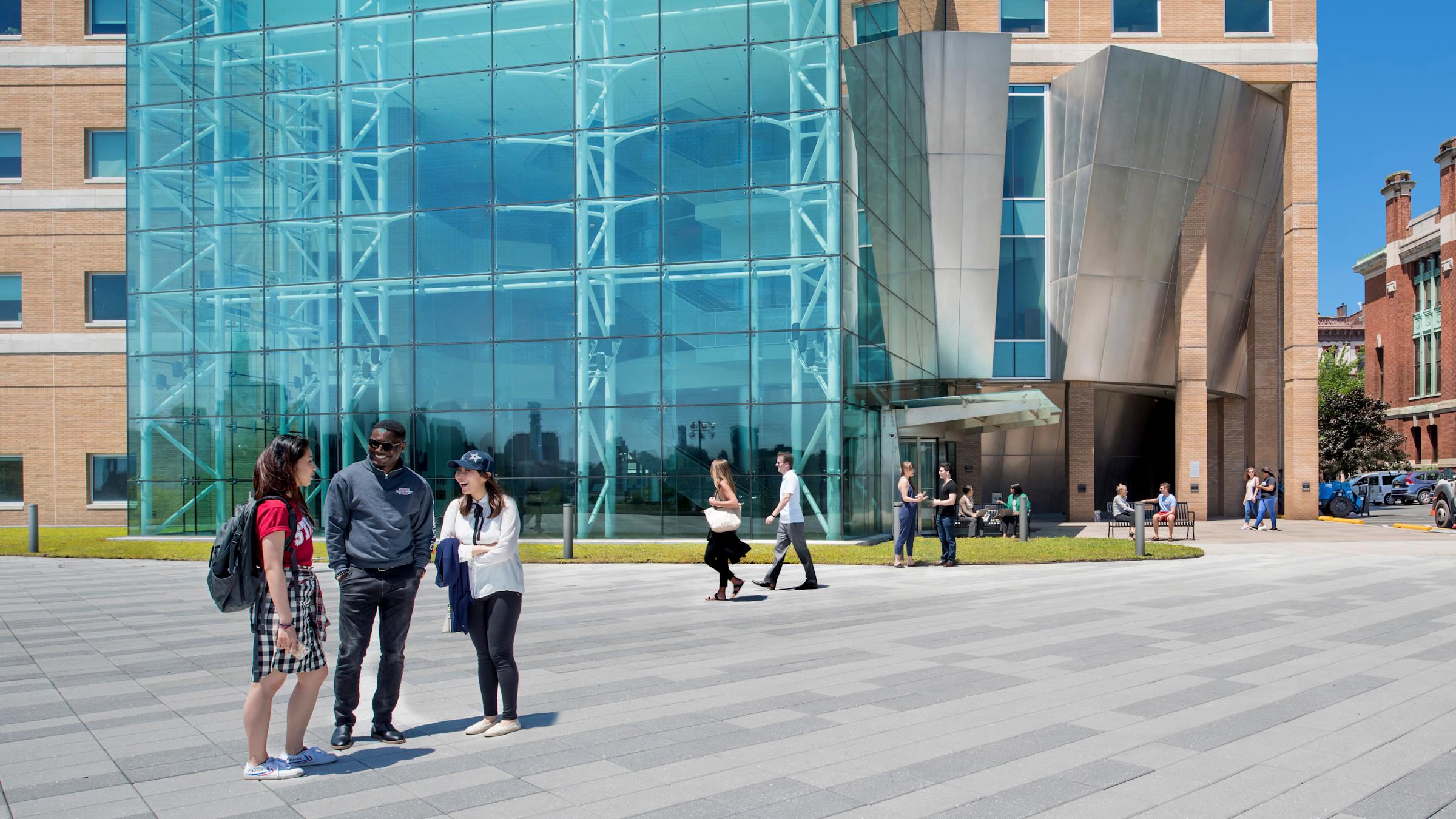 Three students smiling and laughing on plaza outside Babbio Center.