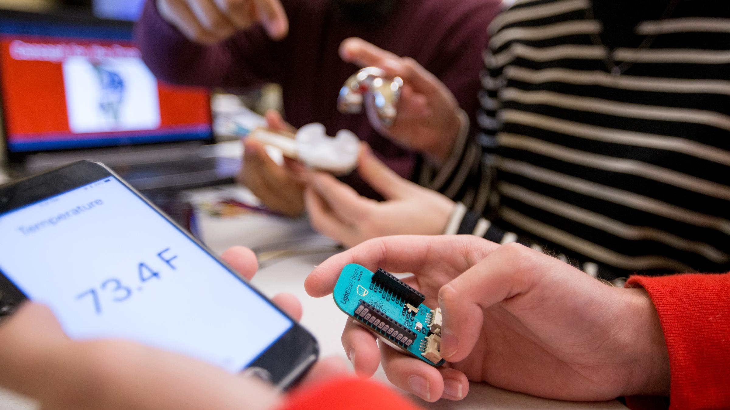 Two students looking at an app on a smartphone displaying current temperature