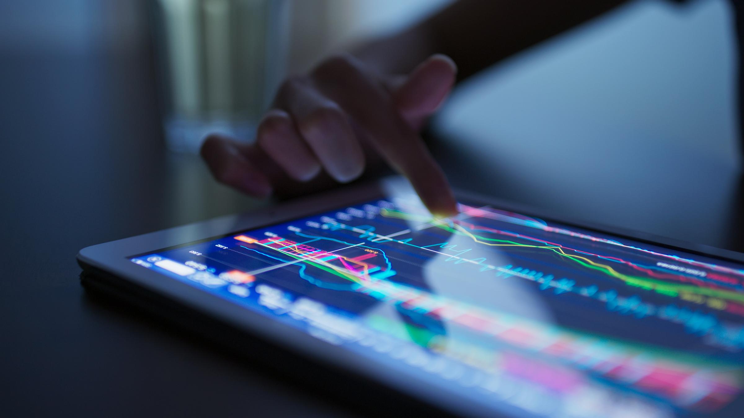 Man working on tablet filled with stock market graphs