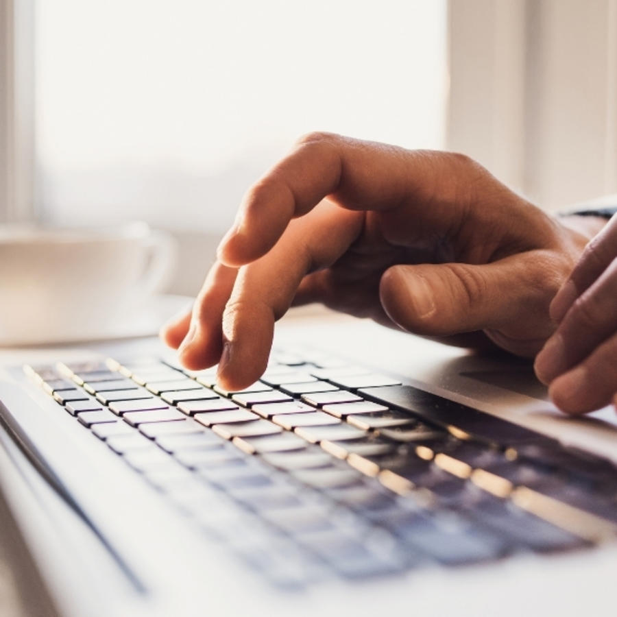Hands typing on laptop.