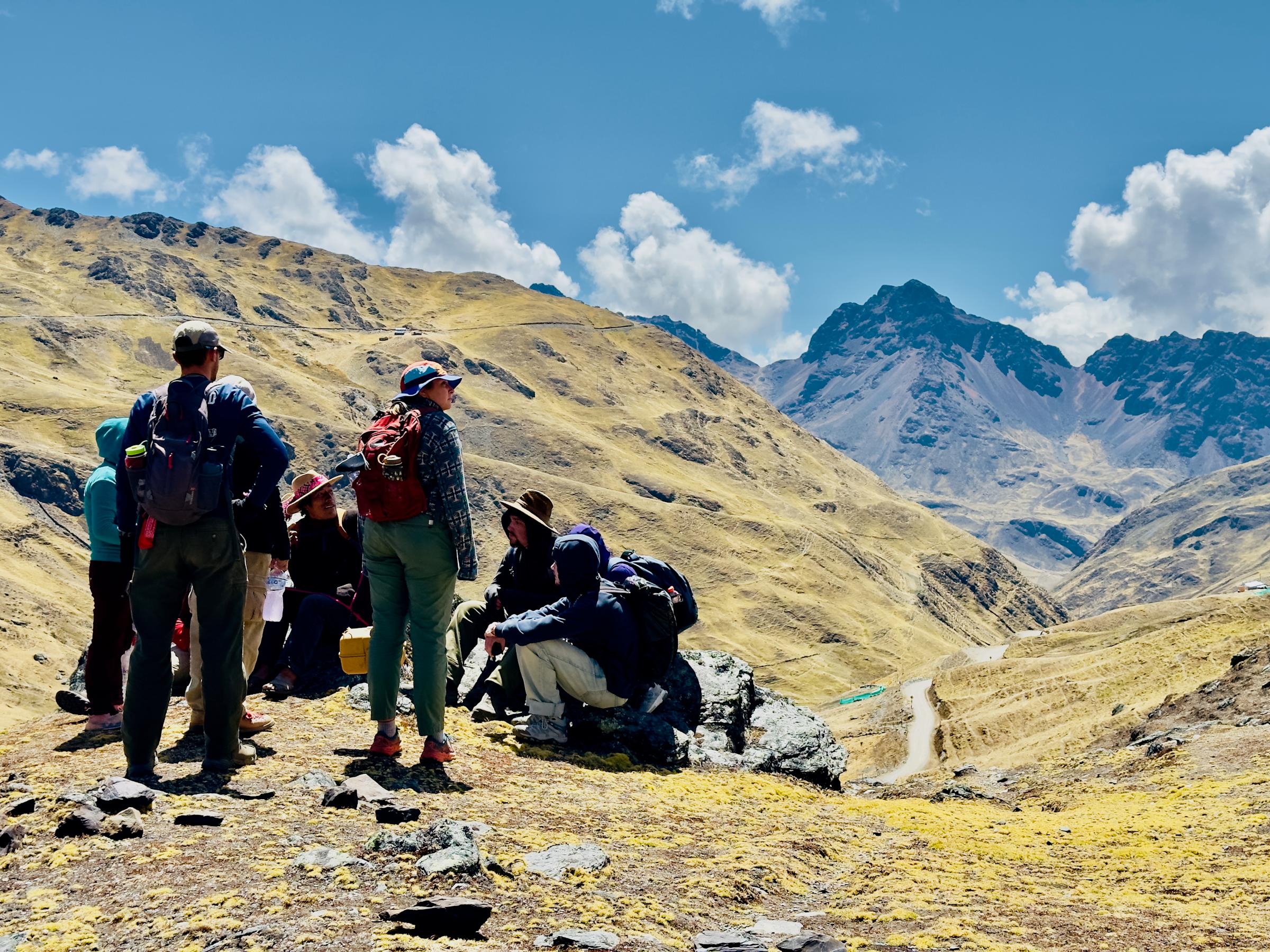Students and guides rest and view a mountain range in Peru.