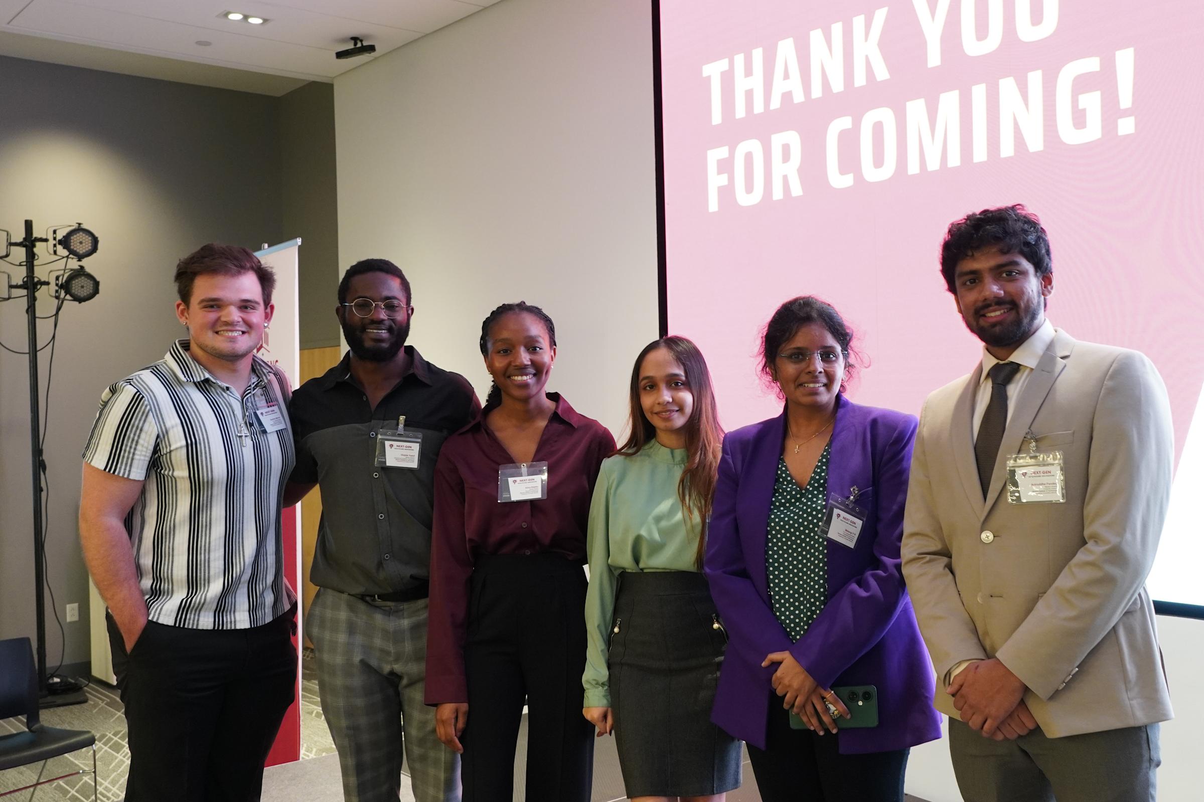 Student volunteers Zachary Marvin, Olajide Yusuf, Shanzi Dsilva, Edna Rajabu, Matangi P R and Aniruddha Pandey pose on stage.