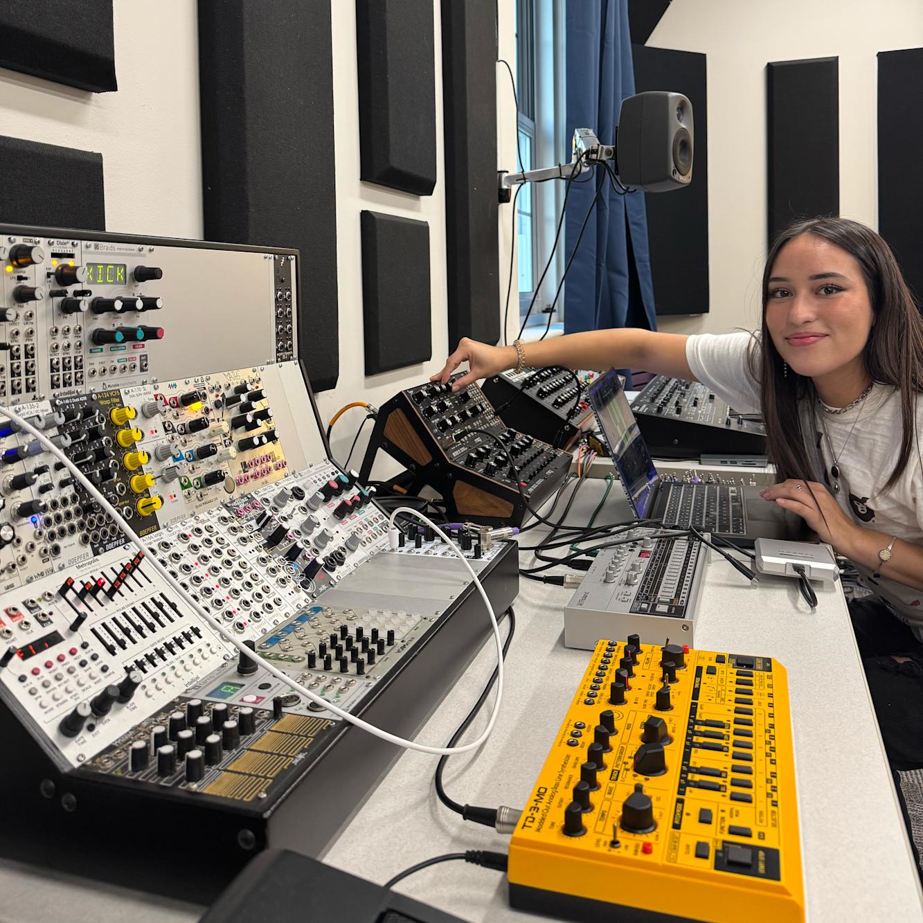 Student working at a sythesizer and mixing board.