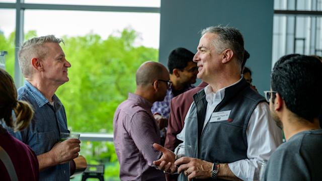 A group of alumni gather and chat with one another at a networking event